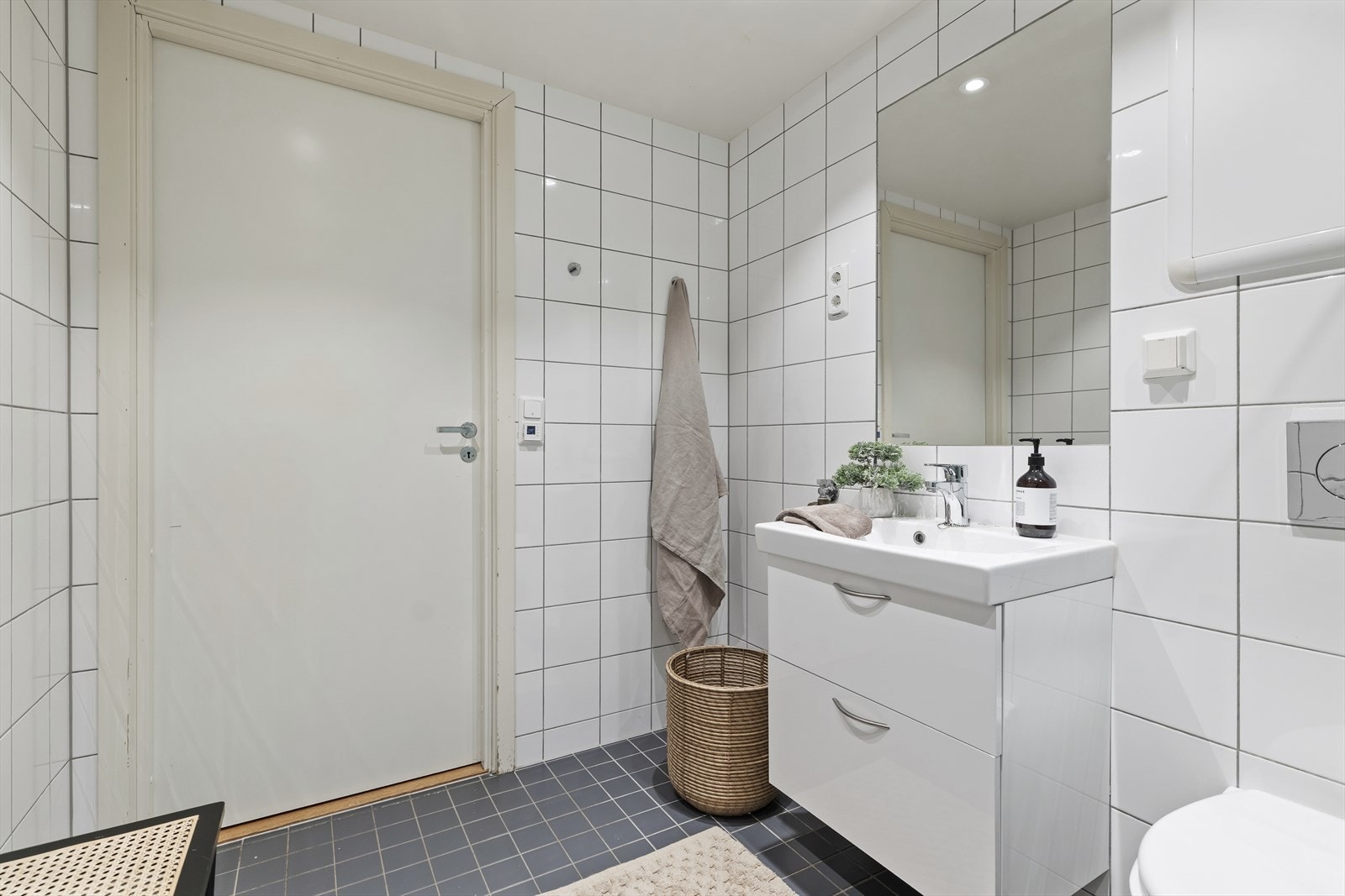 Baderomsinnredningen består av servant med skuffer, vegghengt toalett, dusj med innfellebare dusjdører og opplegg for vaskemaskin Galleribilde