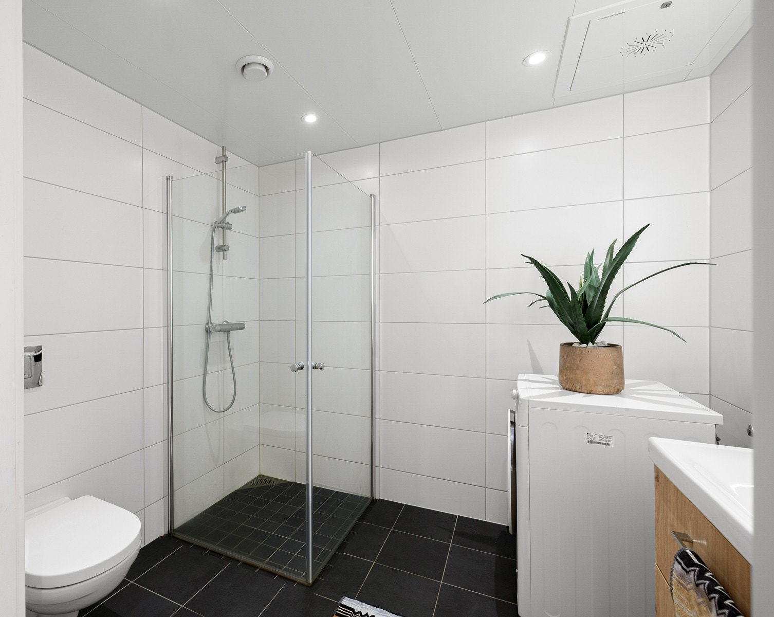 Badet er funksjonelt innredet med dusjhjørne, servantmøbel og opplegg for vaskemaskin. Galleribilde