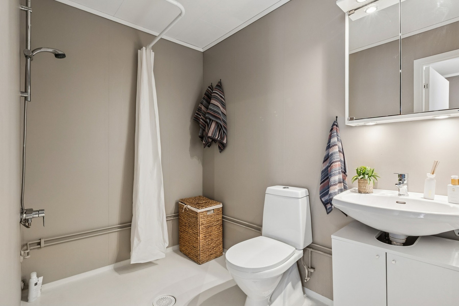 Baderommet har dusj, speilskap med overliggende spotlys, servantskap med malte fronter og servant. Galleribilde