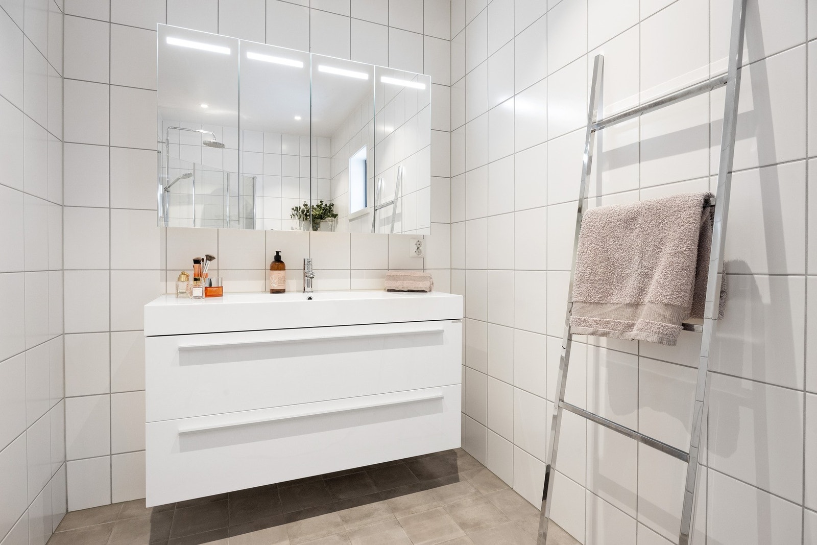 Badet er innredet med dusjnisje, klosett, servant med skuffeseksjon og overskap med speilfronter. Galleribilde