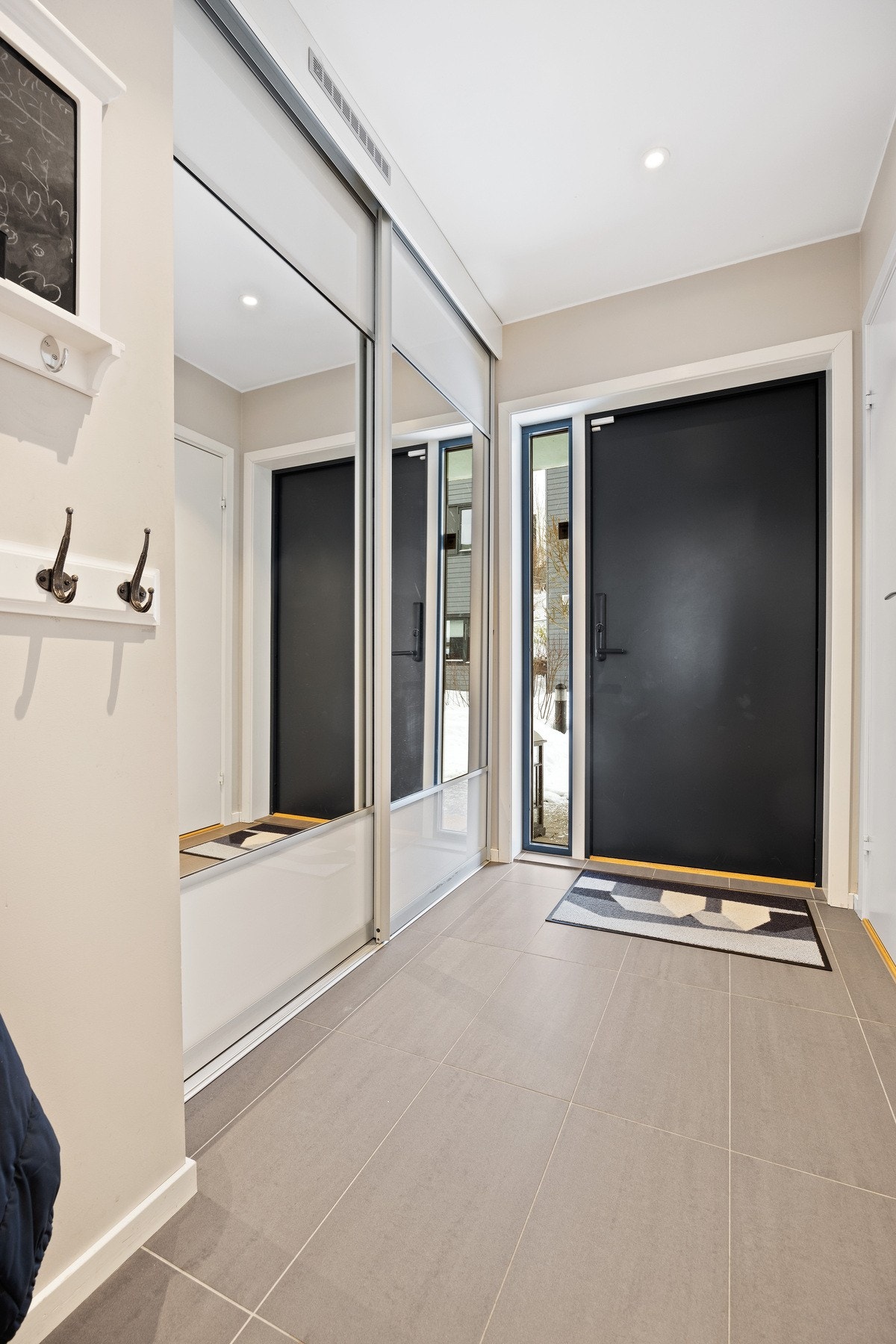 Flislagt entré med skyvedørsgarderobe. Galleribilde