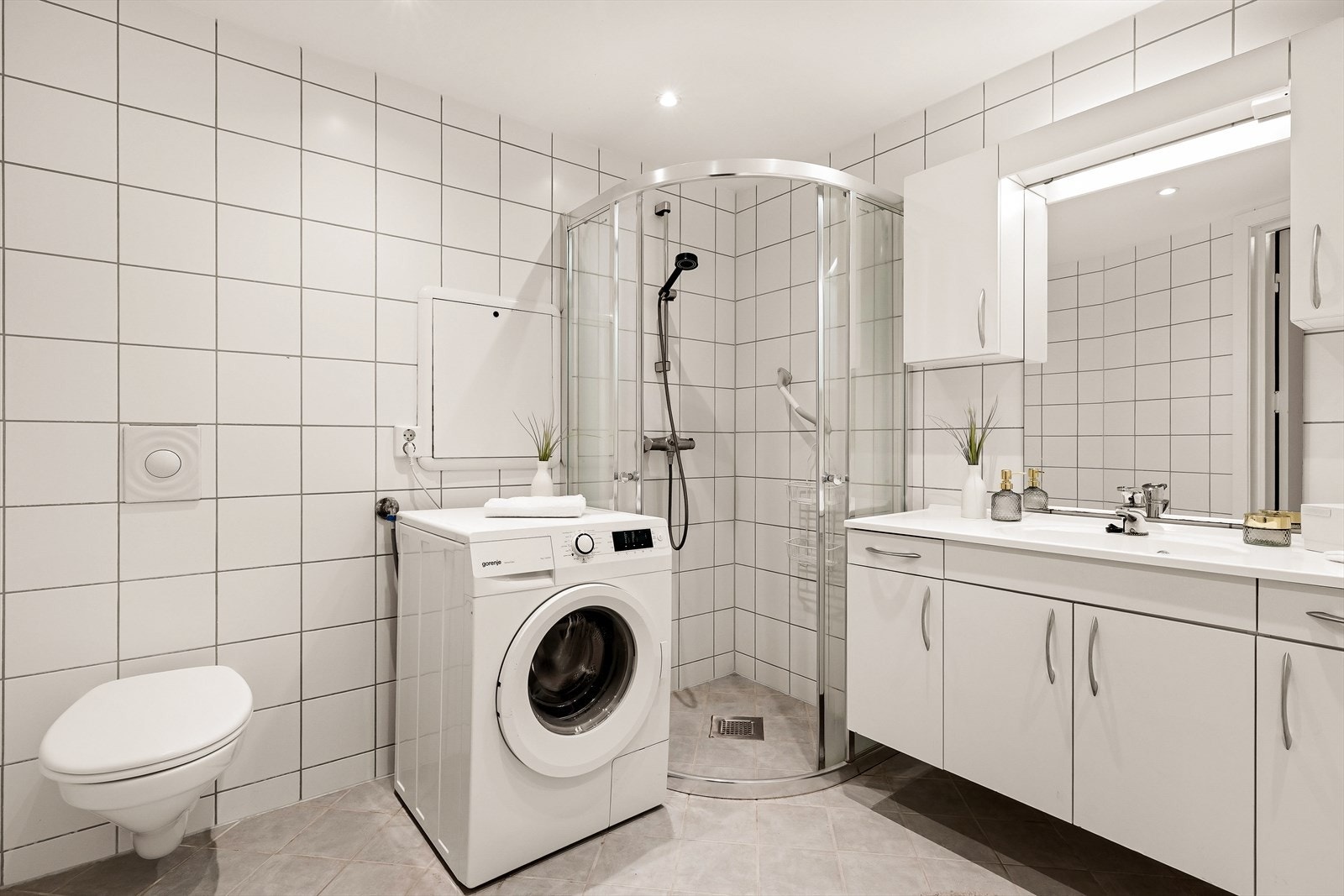 Stilrent, flislagt bad med moderne løsninger som vegghengt toalett, lekkert dusjhjørne og helstøpt servant i elegant innredning med gode skapmuligheter. Praktisk opplegg for vaskemaskin gjør rommet både funksjonelt og innbydende. Galleribilde