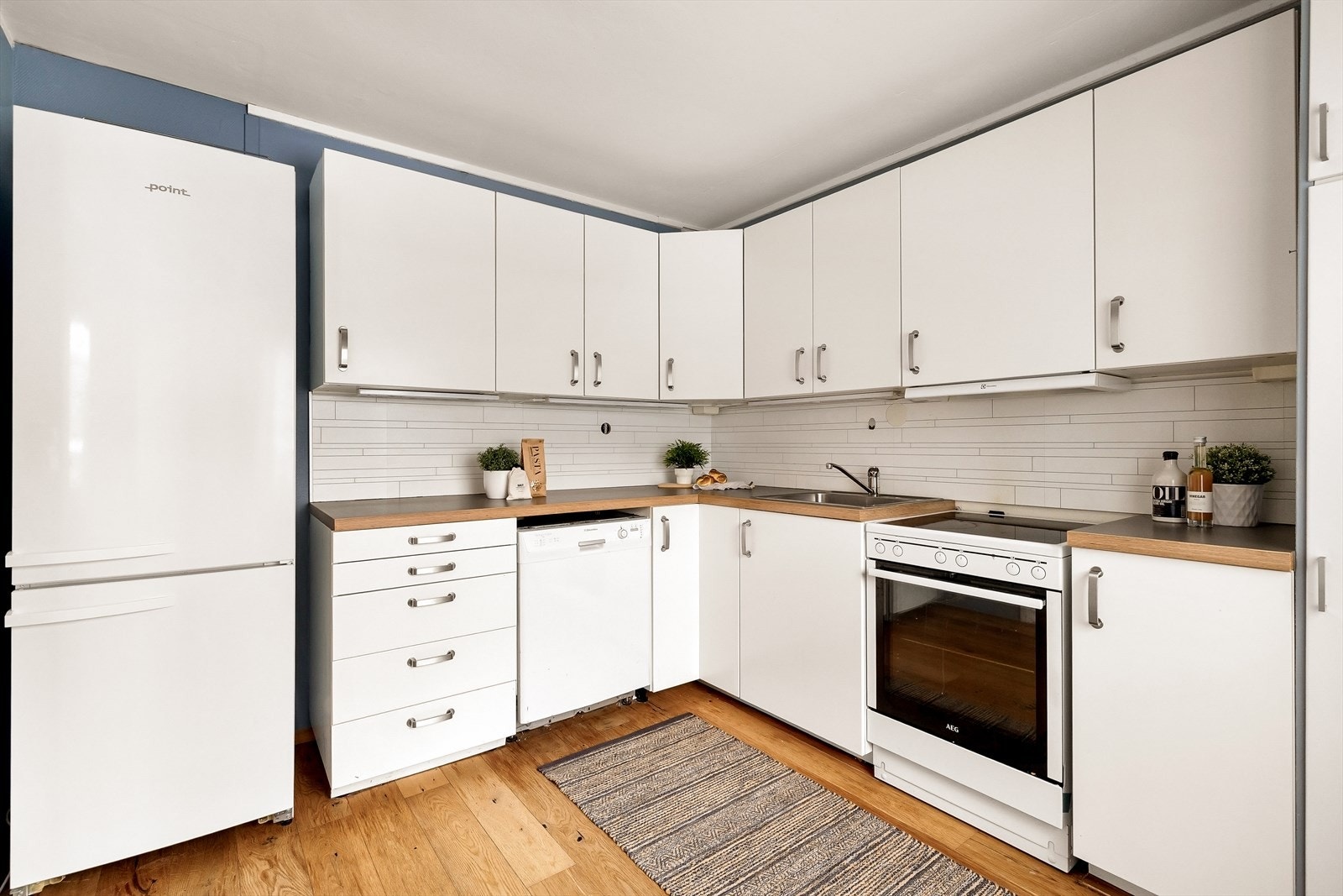 Lyst og pent Ikea kjøkken med malte, slette fronter og laminerte benkeplater. Praktisk opplegg for oppvaskmaskin og godt med arbeids- og skapplass. Galleribilde