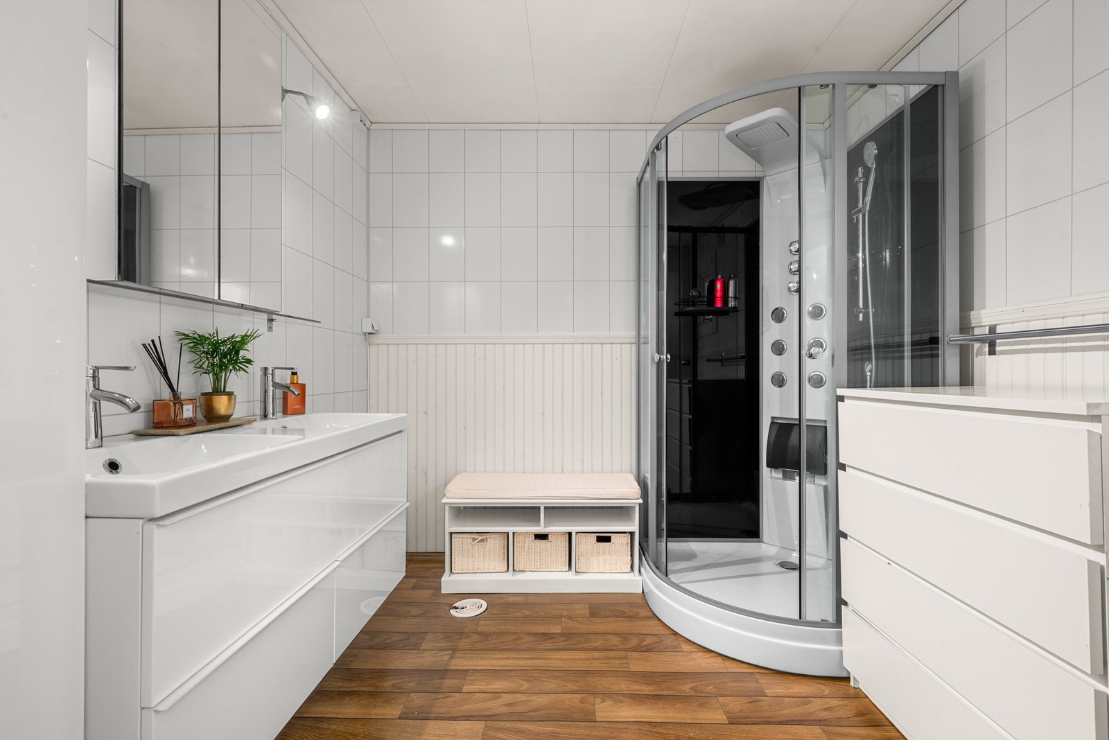 Videre er badet innredet med dobbeltservant med overskap med speil og lys, dusjkabinett og toalett. Galleribilde