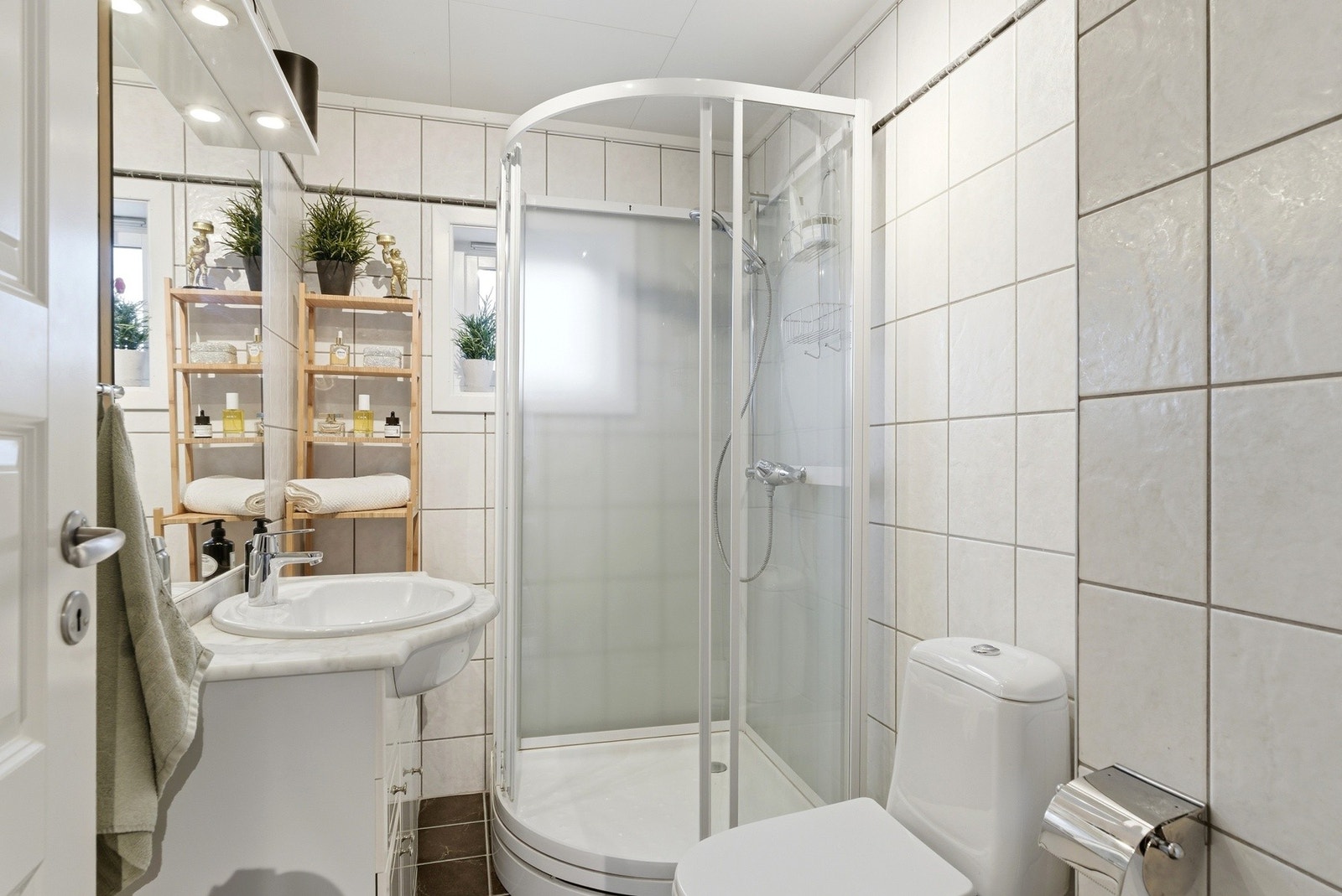 Badet har flislagt gulv med elektriske varmekabler. Det er innredning med nedfelt servant, toalett og dusjkabinett. Galleribilde