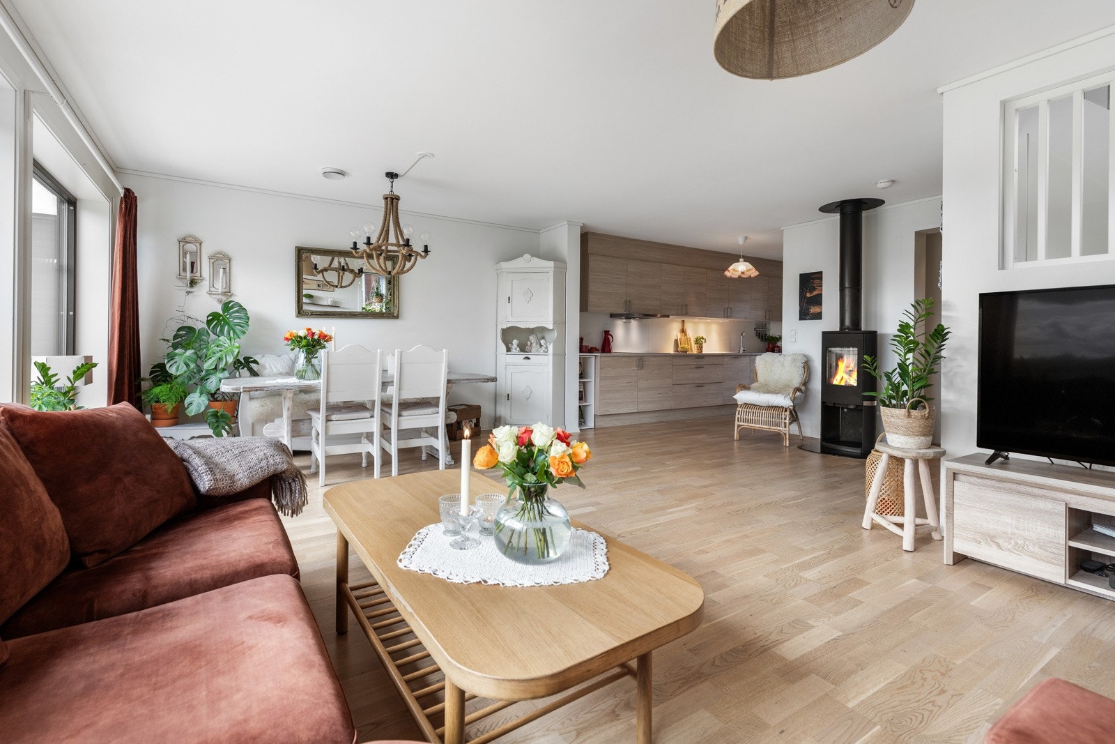 Lyst og romslig oppholdsrom med åpen kjøkkenløsning, peis og store vindusflater. Galleribilde