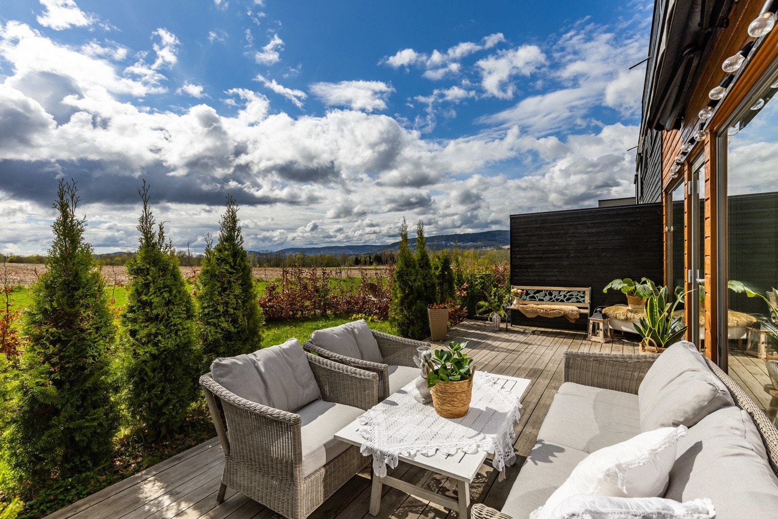 Terrasse med utsikt over grønt landskap og skogskledde åser i horisonten Galleribilde