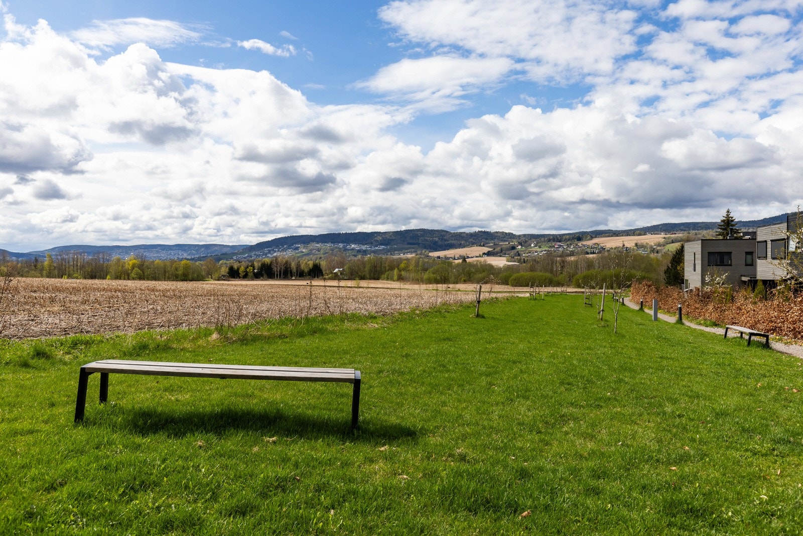 Åpent grøntområde med benk, utsikt mot åser og spredt bebyggelse Galleribilde