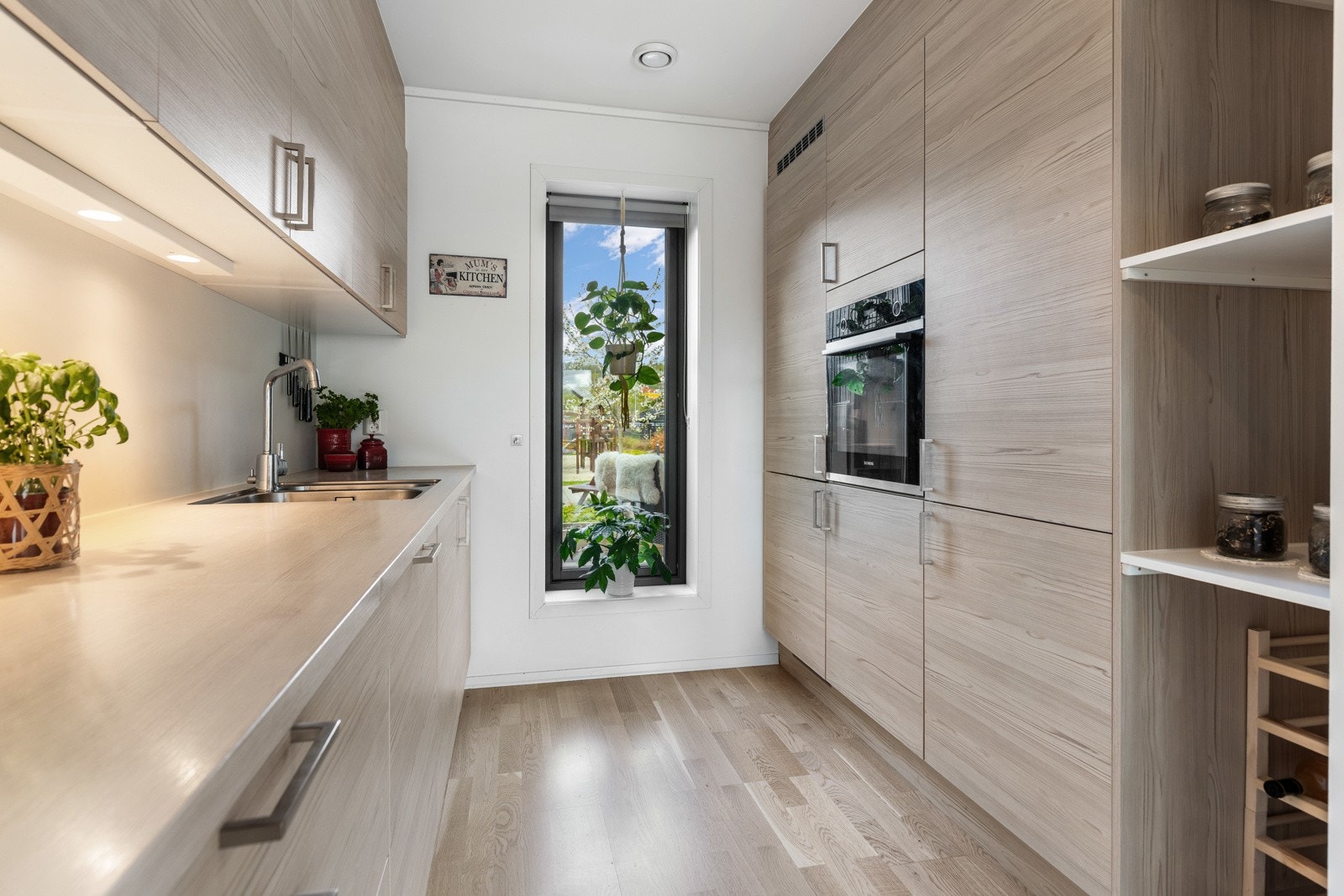 Moderne kjøkken med lyse overflater og integrerte hvitevarer. Store vinduer gir rikelig med naturlig lys. Galleribilde