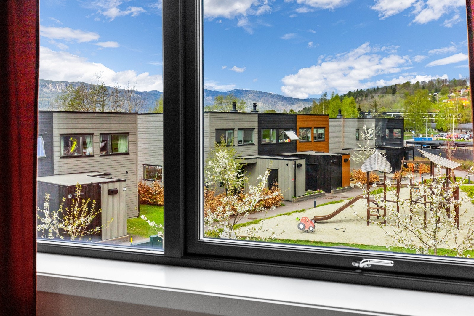 Utsikt mot nærområdet og lekeplass, omgitt av frodig natur. Galleribilde