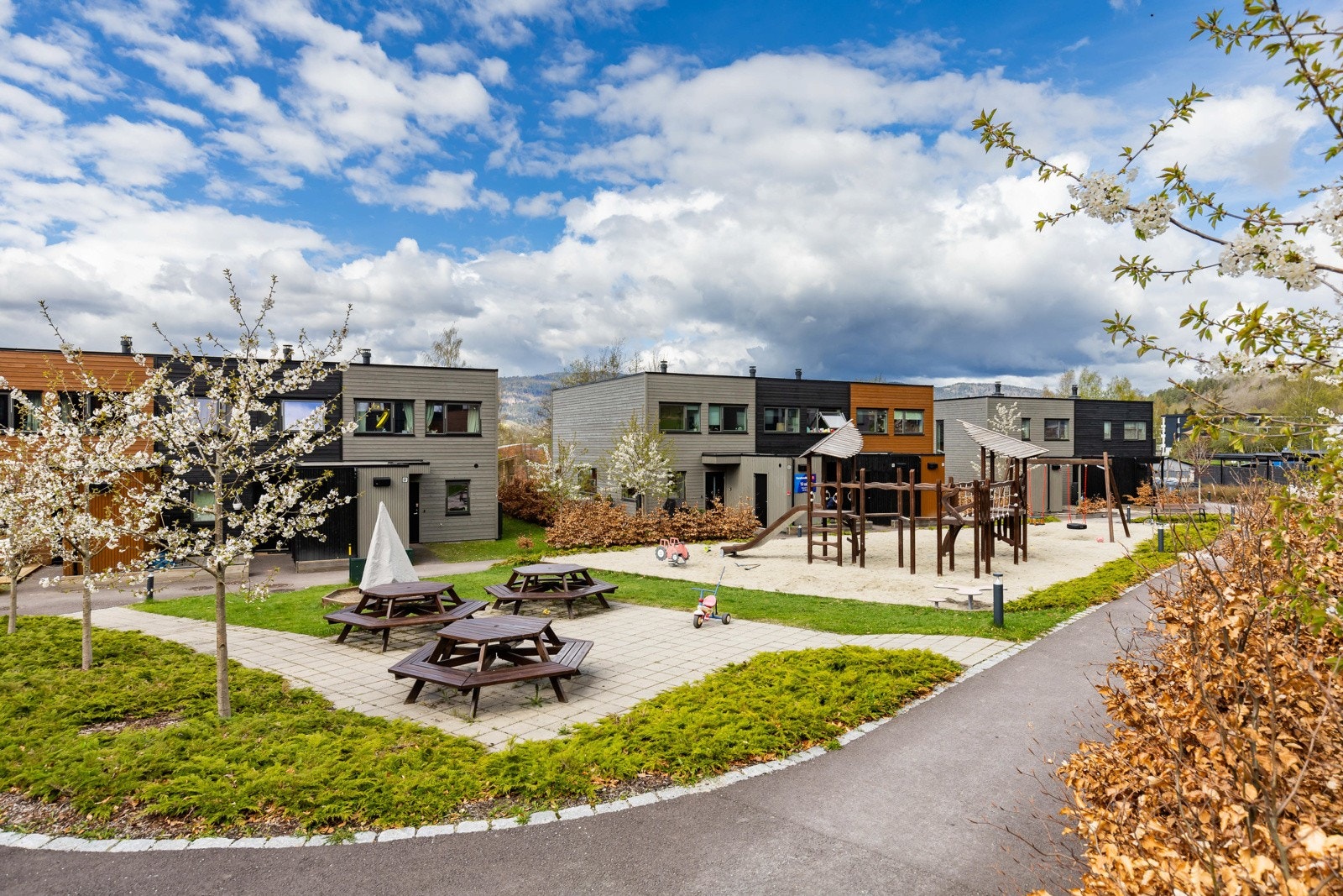 Moderne rekkehus med lekeplass og sitteområder i et barnevennlig nabolag. Galleribilde