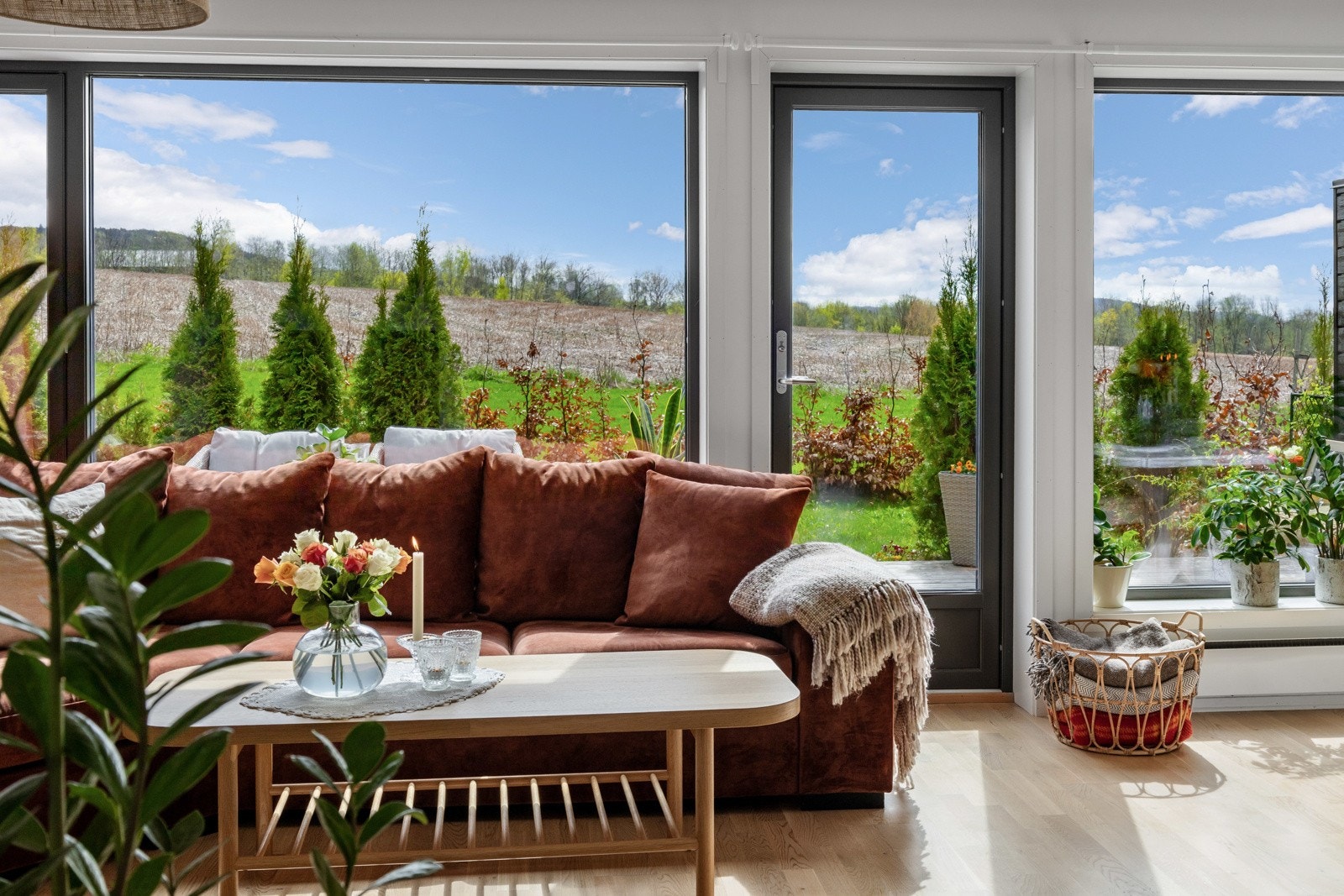 Store vinduer gir flott utsikt til et grønt område med trær og åpen himmel. Galleribilde