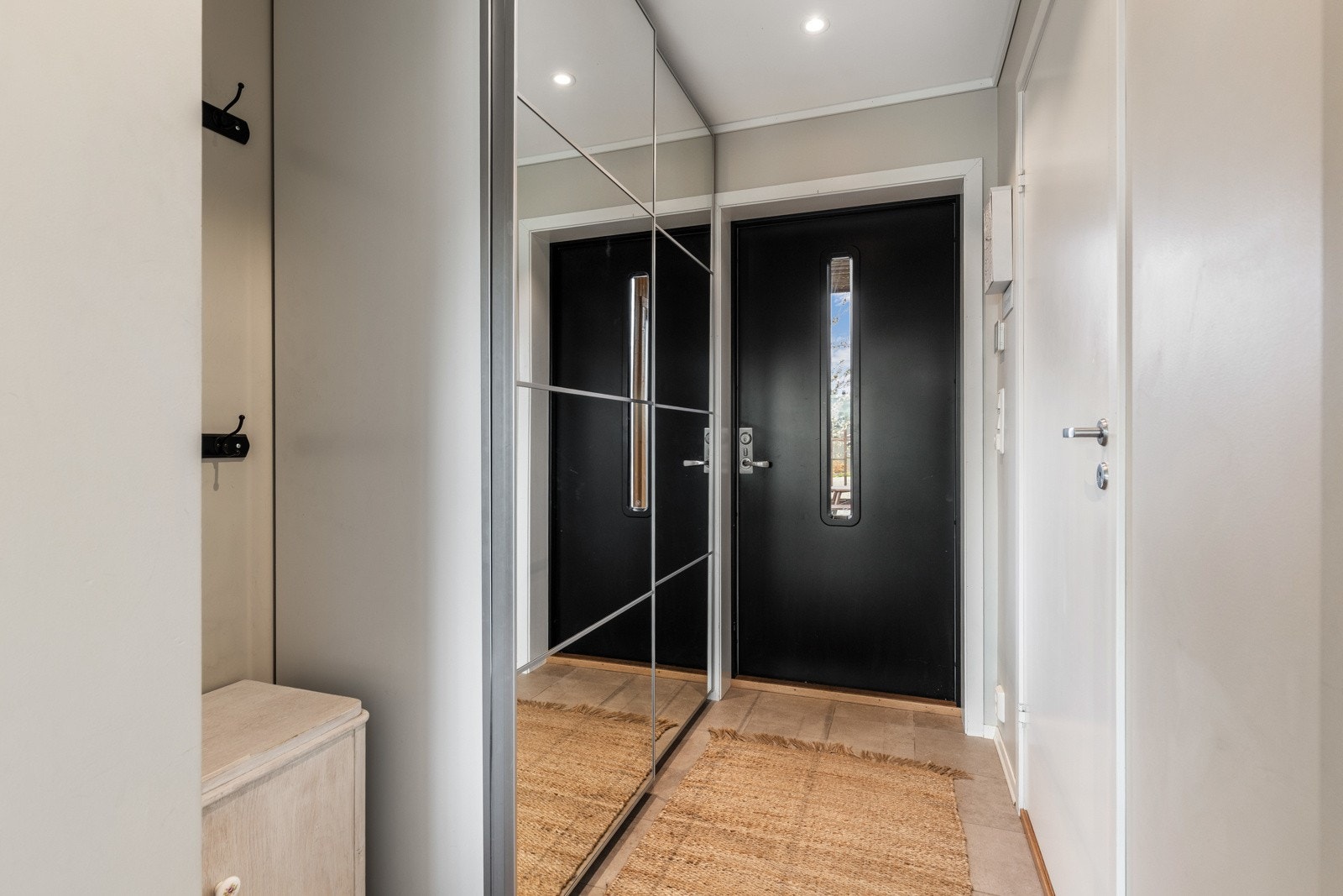 Inngangsparti med speilskyvedørsgarderobe, flislagt gulv og downlights i taket. Galleribilde