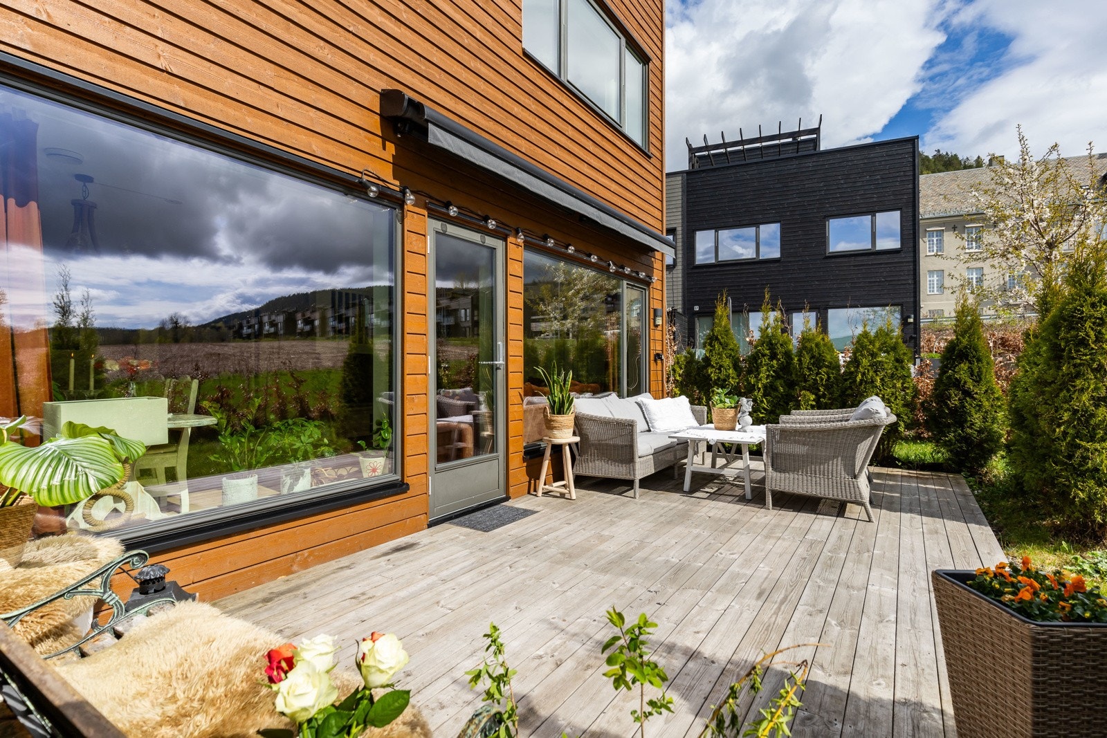 Terrasse med sittegruppe og utsikt mot grønne omgivelser. Store vinduer gir godt lys inn i boligen. Galleribilde
