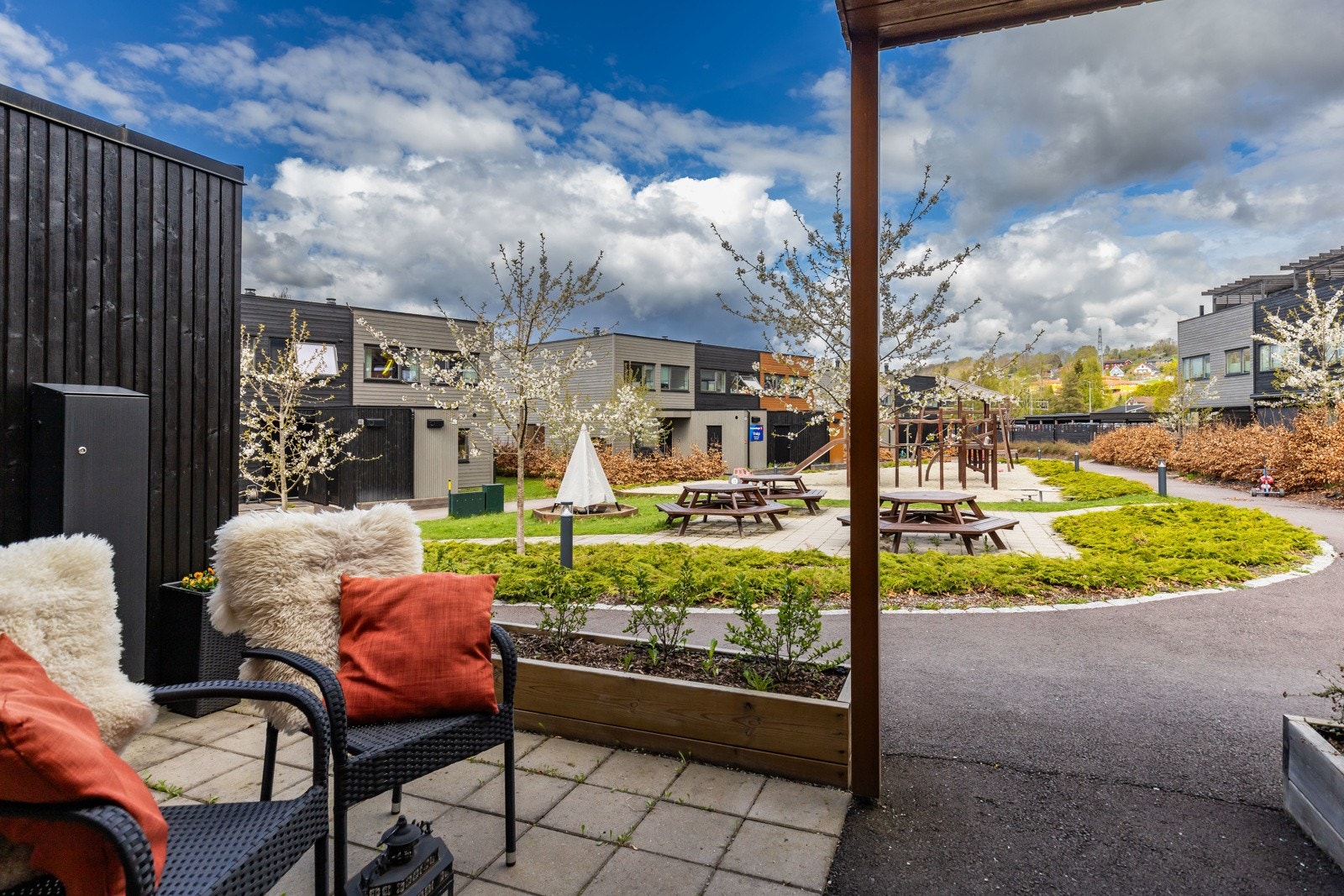 Utsikt mot nærområdet og felles uteområde med lekeplass og benker. Galleribilde