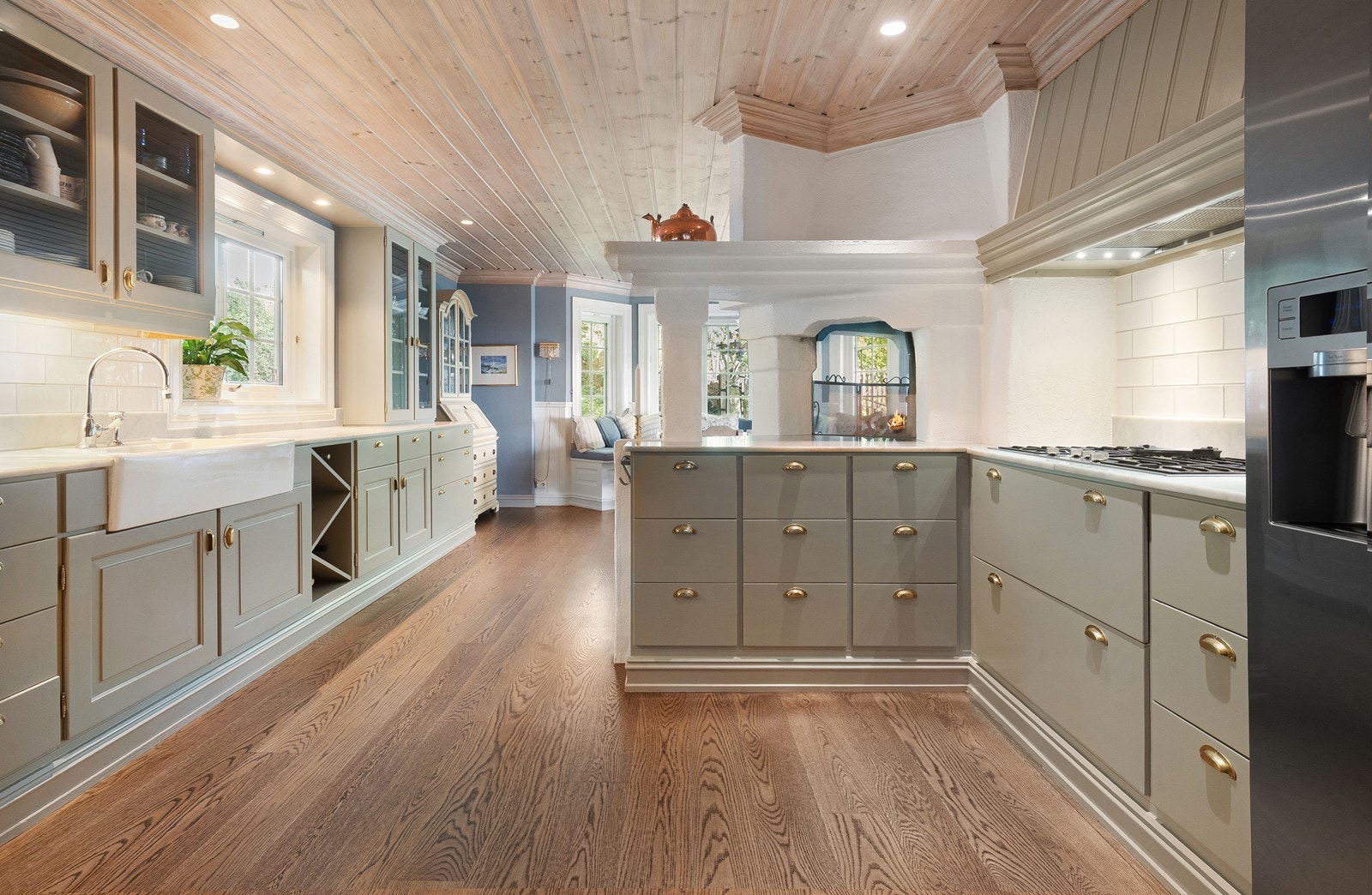 Koselig peis med gjennomsyn og klassisk solid kjøkkeninnredning innover rommet gjennomgående mot trappehallen Galleribilde