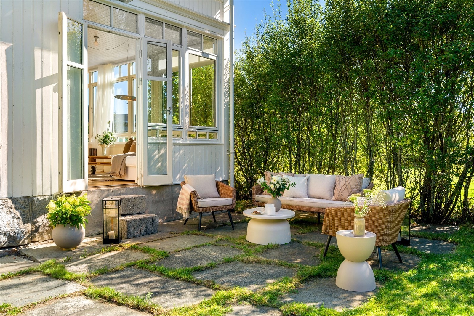 Stuen åpner seg mot hagen, med utemøbler som gjør uteområdet til en naturlig forlengelse av oppholdsrommet. Galleribilde