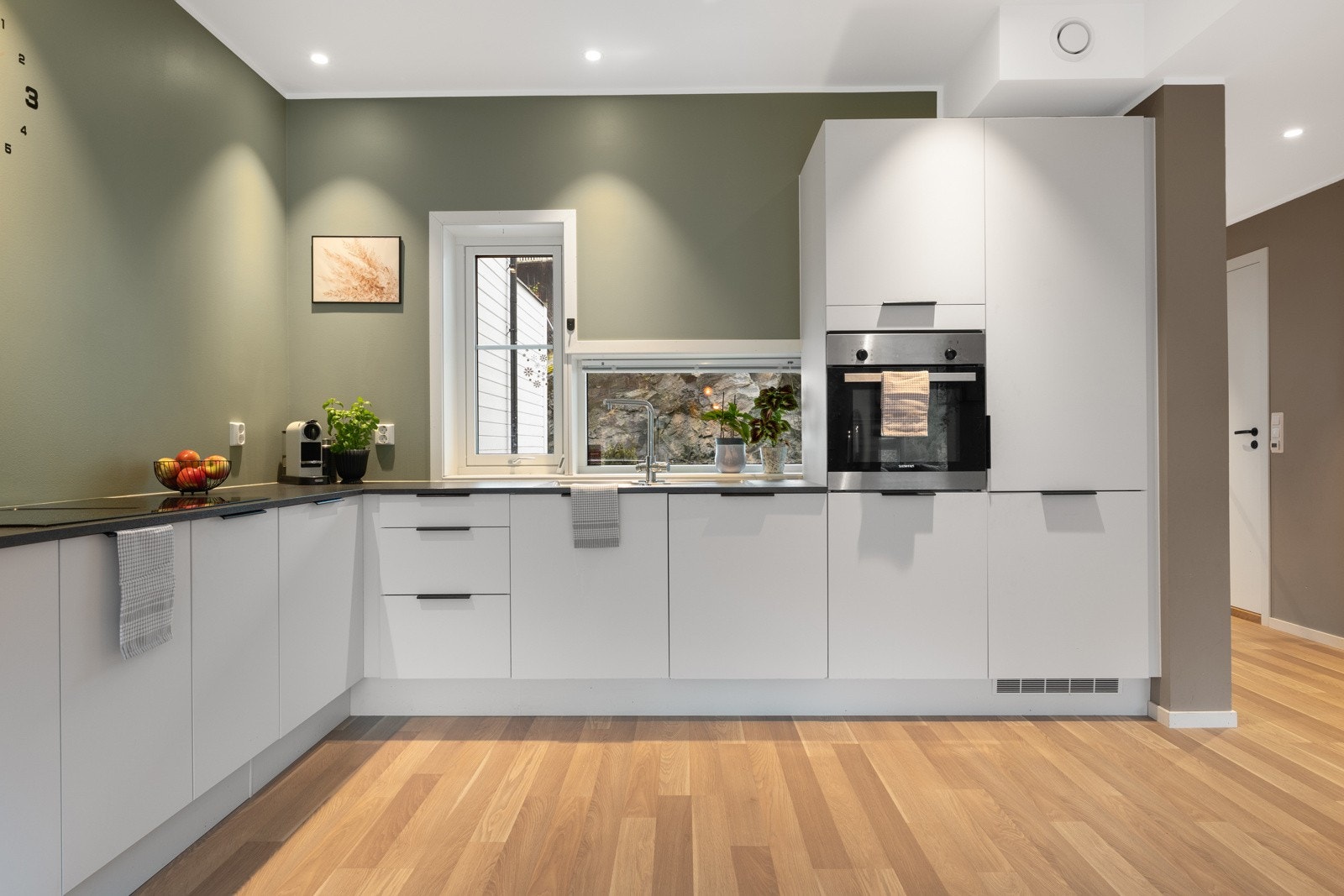 Her er det slette hvite fronter og laminat benkeplate. Utformingen sørger for rikelig med skap- og benkeplass. Galleribilde