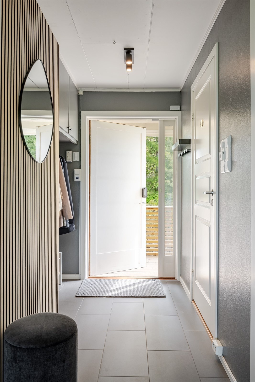 Når du entrer boligen kommer du inn i en flott entré med plass til sko og oppheng av yttertøy. Moderne standard med mørke fliser på gulv med gulvvarme og malte overflater kombinert med stilige trespiler. Galleribilde