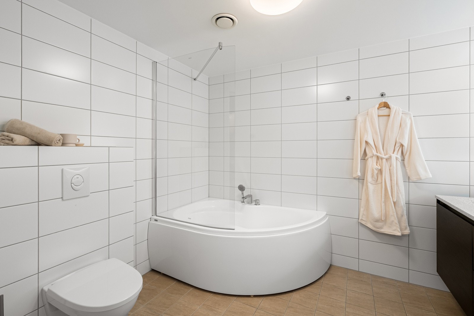 Badet har badekar med dusj, vegghengt toalett, speil med belysning og dobbel servant med flotte detaljer. Galleribilde