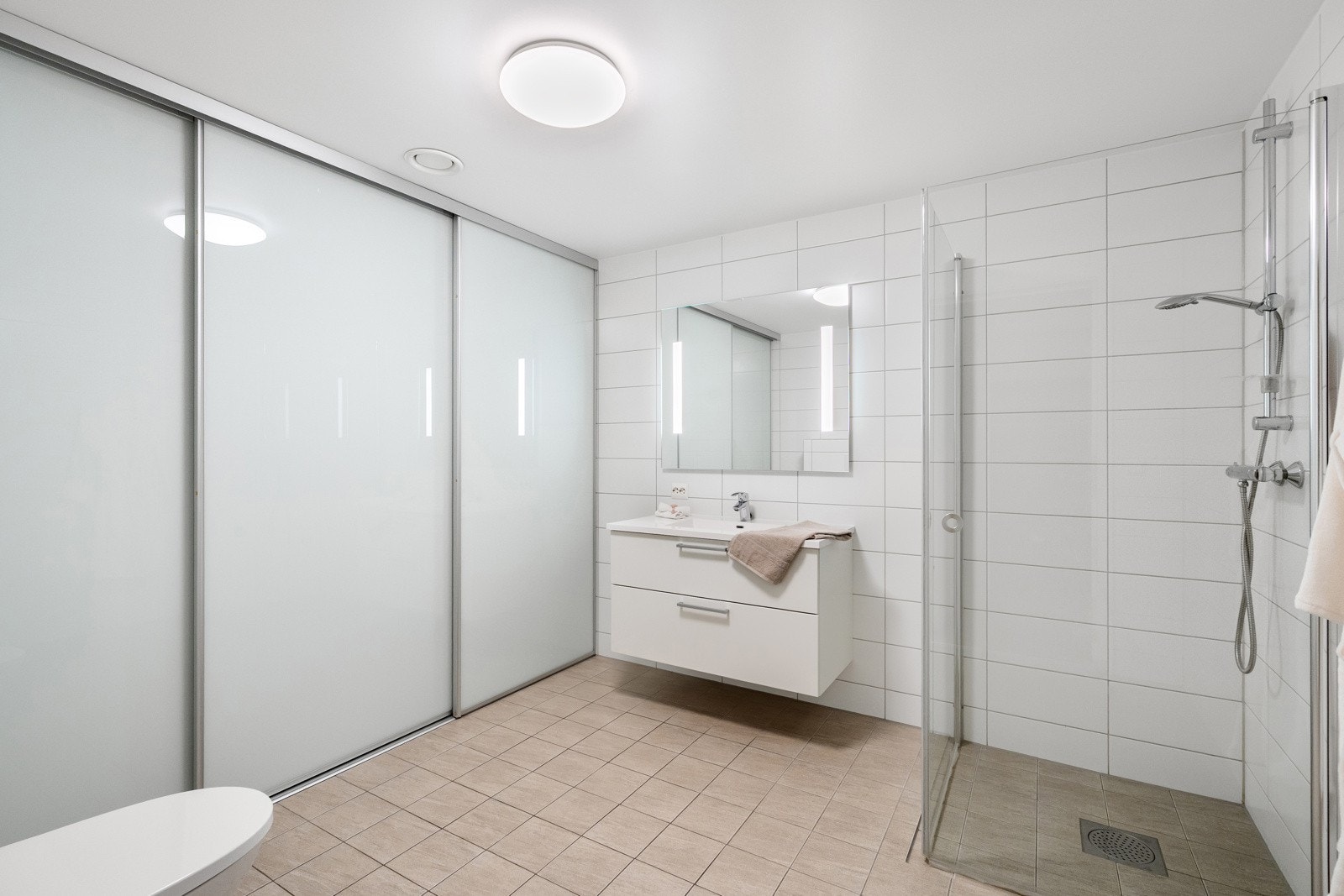 Moderne innredet med vegghengt toalett, dusjhjørne, hel servant og speil med belysning. Praktisk vaskeromsløsning med utslagsvask og skyvedører som gir en fin oppdeling av sonene. Galleribilde