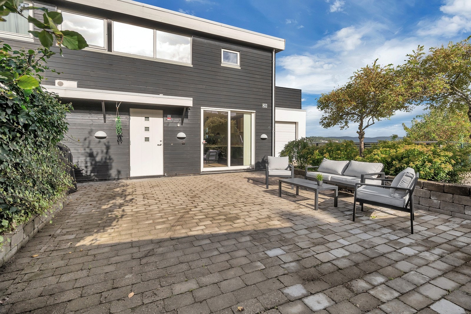 Inngangspartiet som er innkranset med beplantning og hekk som gir et lunt og trivelig utemiljø. Tomten er fellesareal for seksjon 1 og 2. Galleribilde