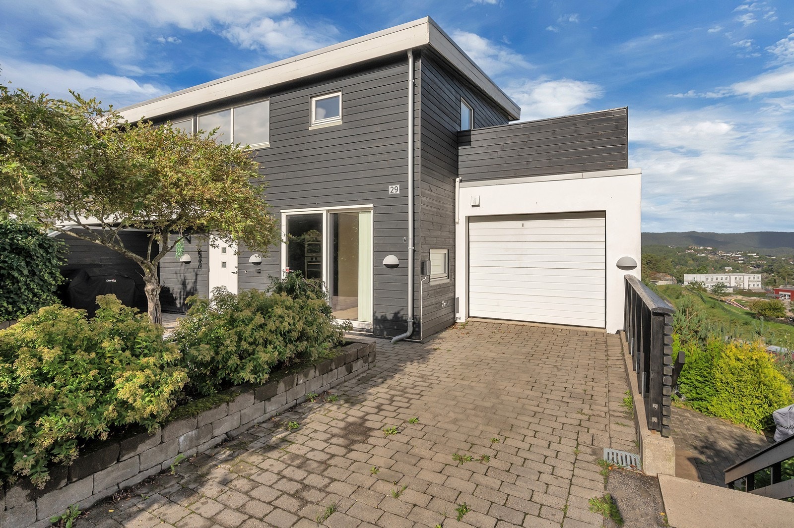 Dette er en moderne del av tomannsbolig over to plan med blant annet garasje og nydelig utsikt. Det er montert elbillader på husveggen foran garasjen. Galleribilde