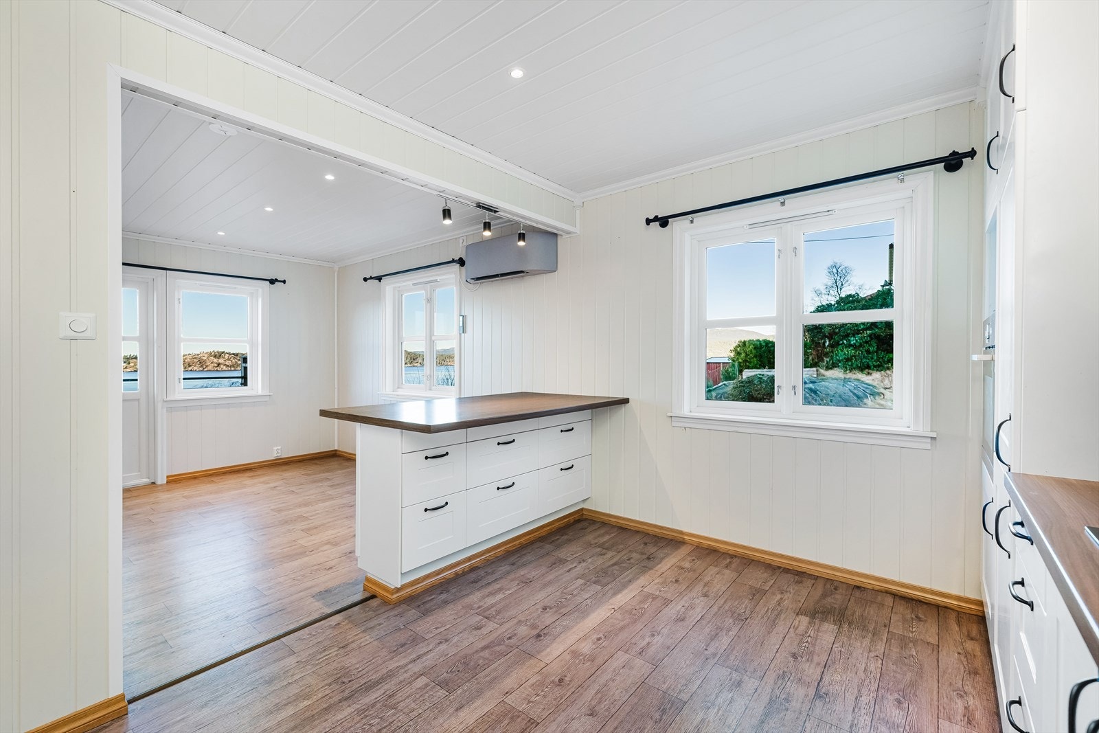 Delvis åpen løsning mellom stue og kjøkken. Nydelig utsikt fra kjøkkenøyen mot sjø. Galleribilde