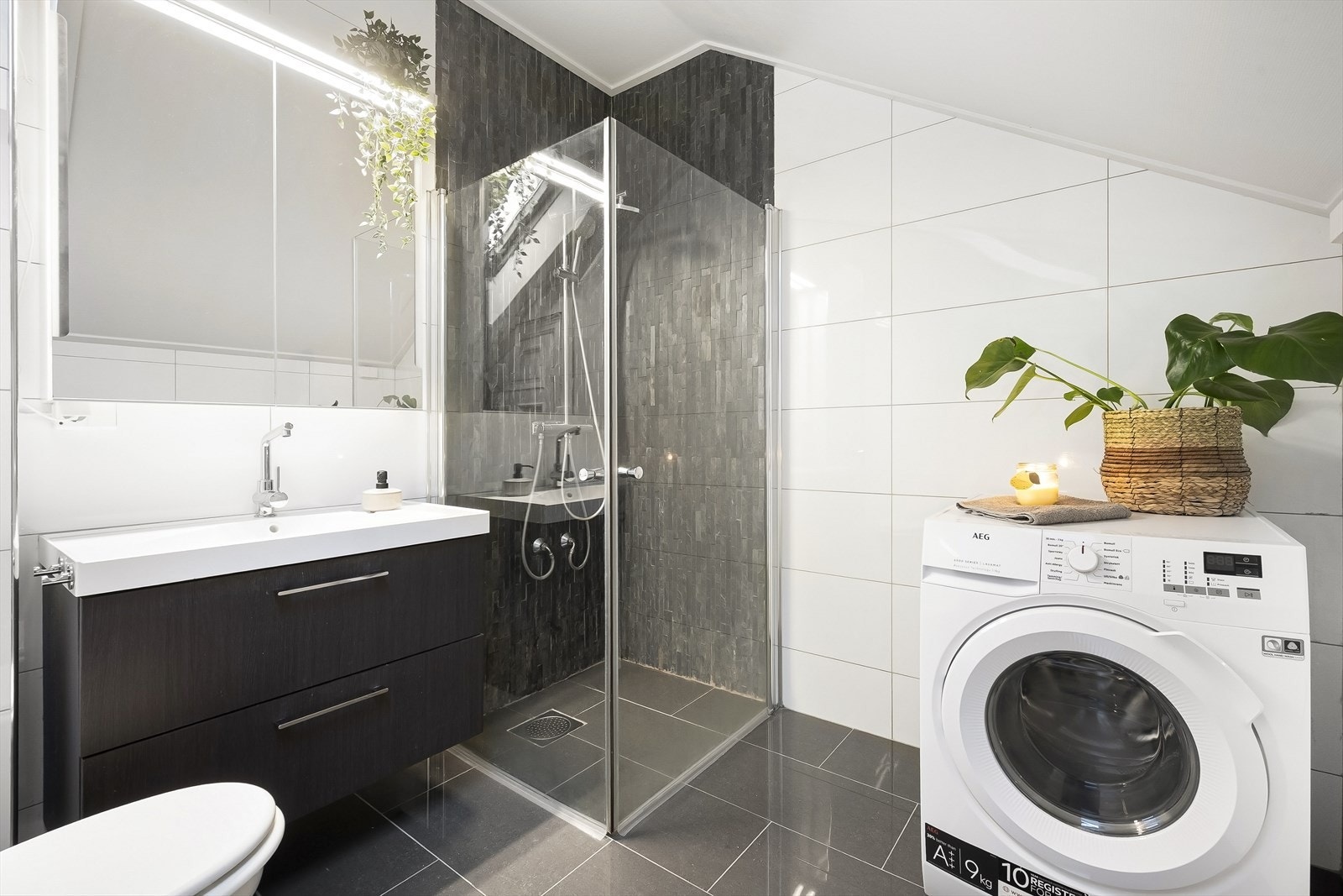 Flott, tidløst bad med flislagte overflater, elektrisk gulvvarme og opplegg for vaskemaskin. Galleribilde