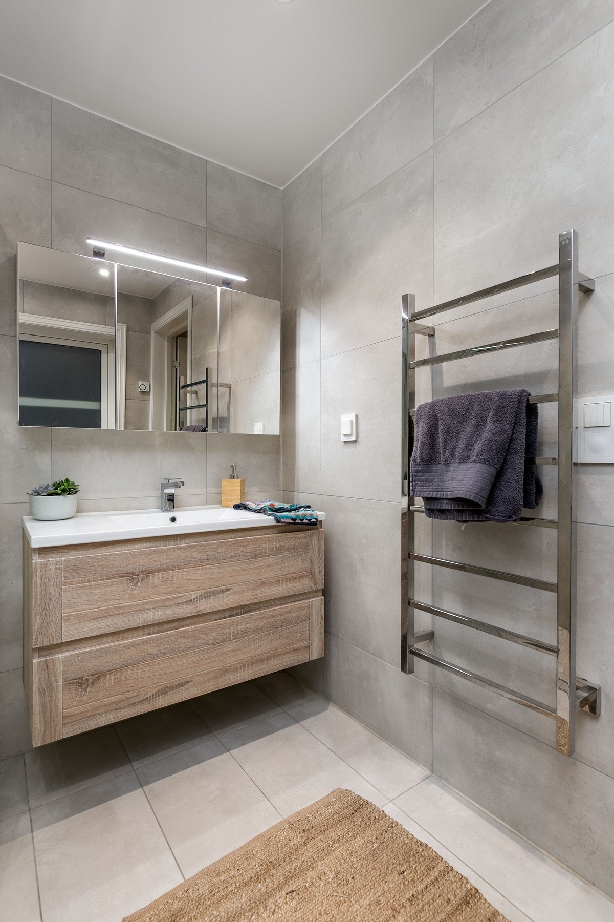 Moderne fliser på vegg. Innredningen består av servantinnredning med skuffer, med glatte fronter. Galleribilde