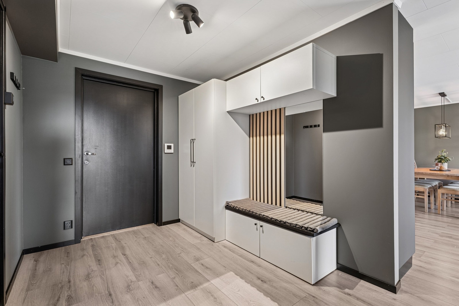 Entréen ønsker velkommen med en stilig spilevegg og speil som gir både et moderne preg og en praktisk oppbevaringsløsning. Galleribilde