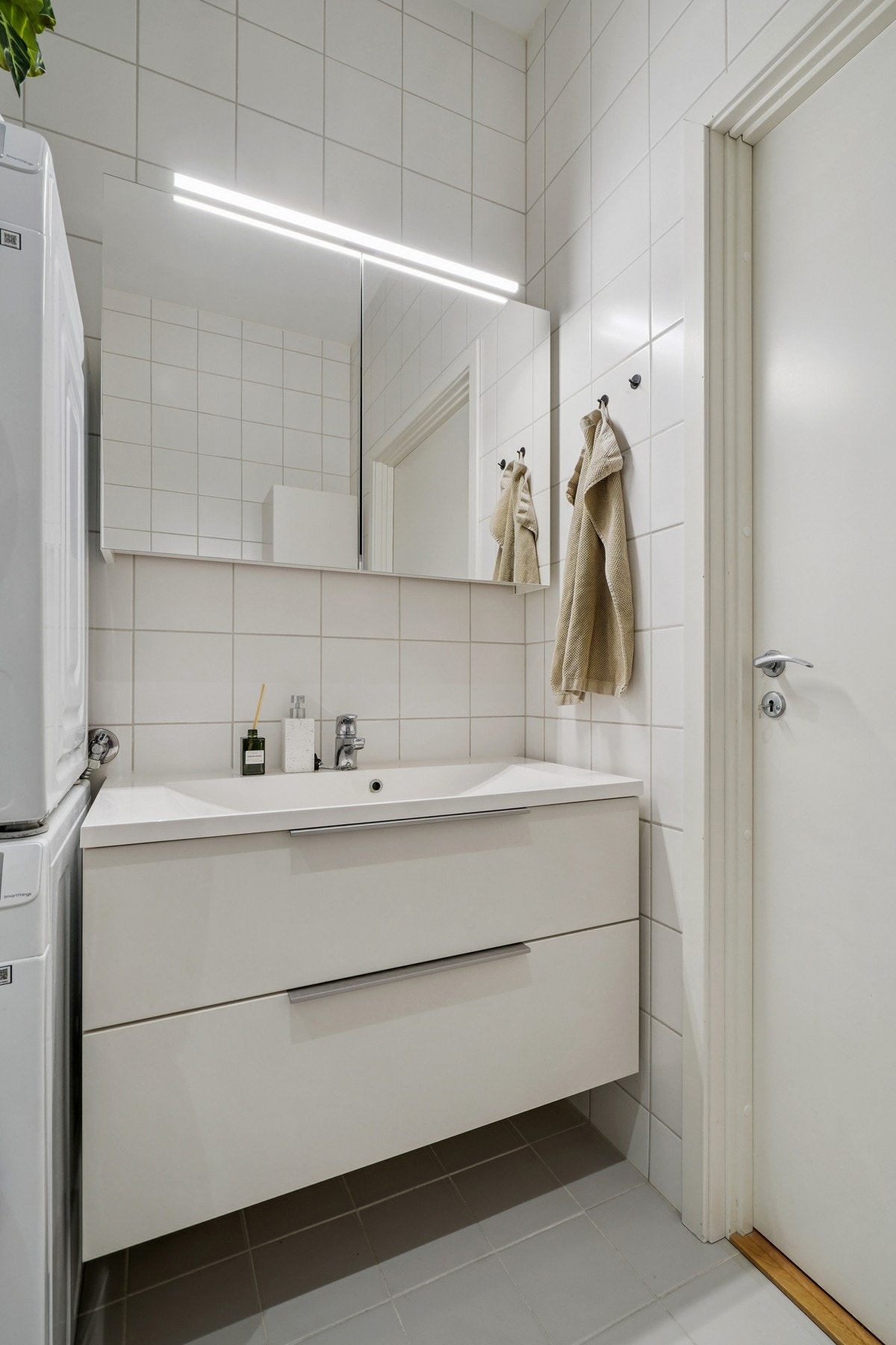 Servantinnredning med to skuffeseksjoner, heldekkende servant og speilskap med belysning over. Galleribilde