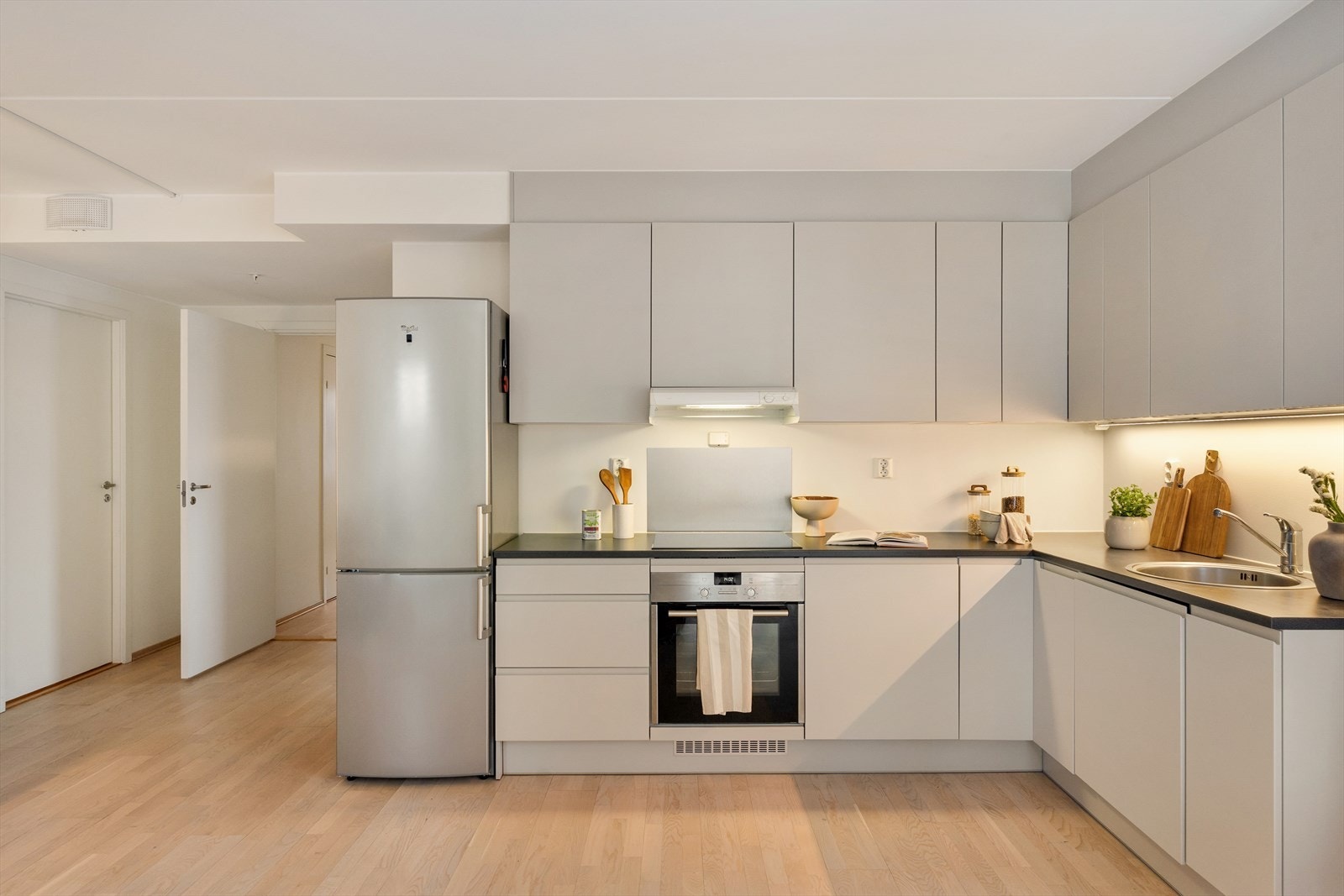 Pen kjøkkeninnredning fra Arens med lakkerte fronter og laminert benkeplate med overliggende oppvaskkum og ettgreps blandebatteri fra Alterna. Galleribilde