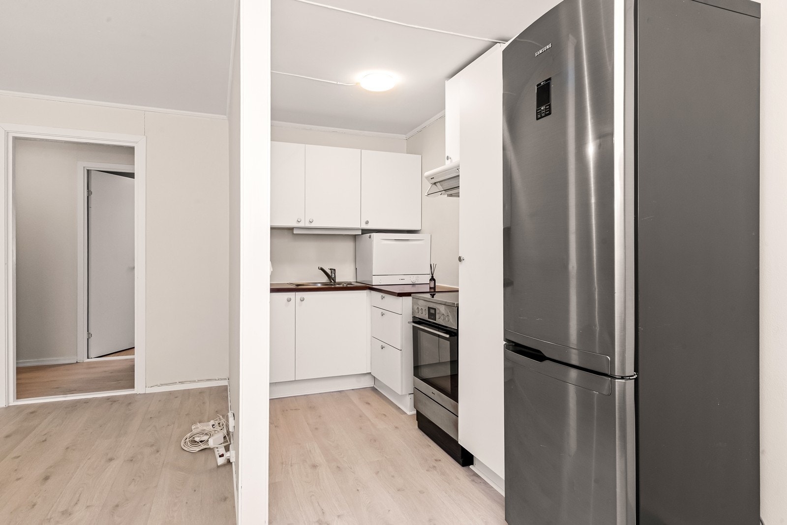 Lyst kjøkken med mye skap og benkeplass. Galleribilde