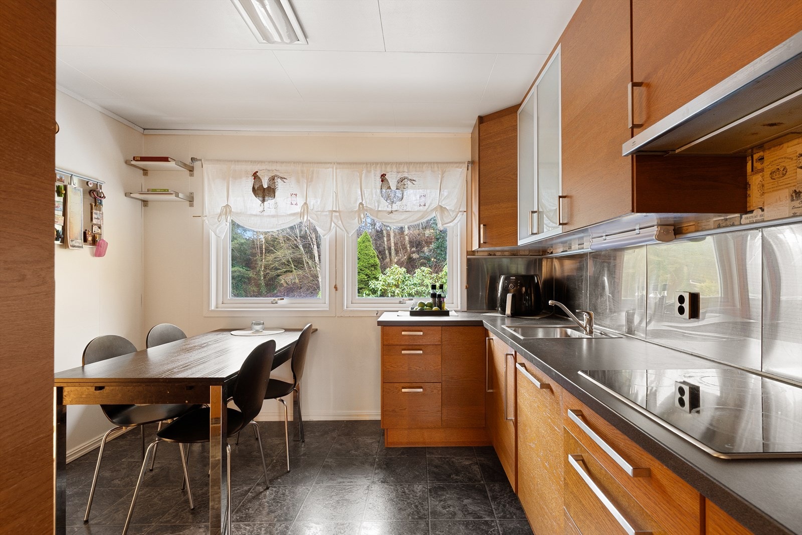 Innbydende kjøkken med brune fronter og mørk benkeplate. Galleribilde