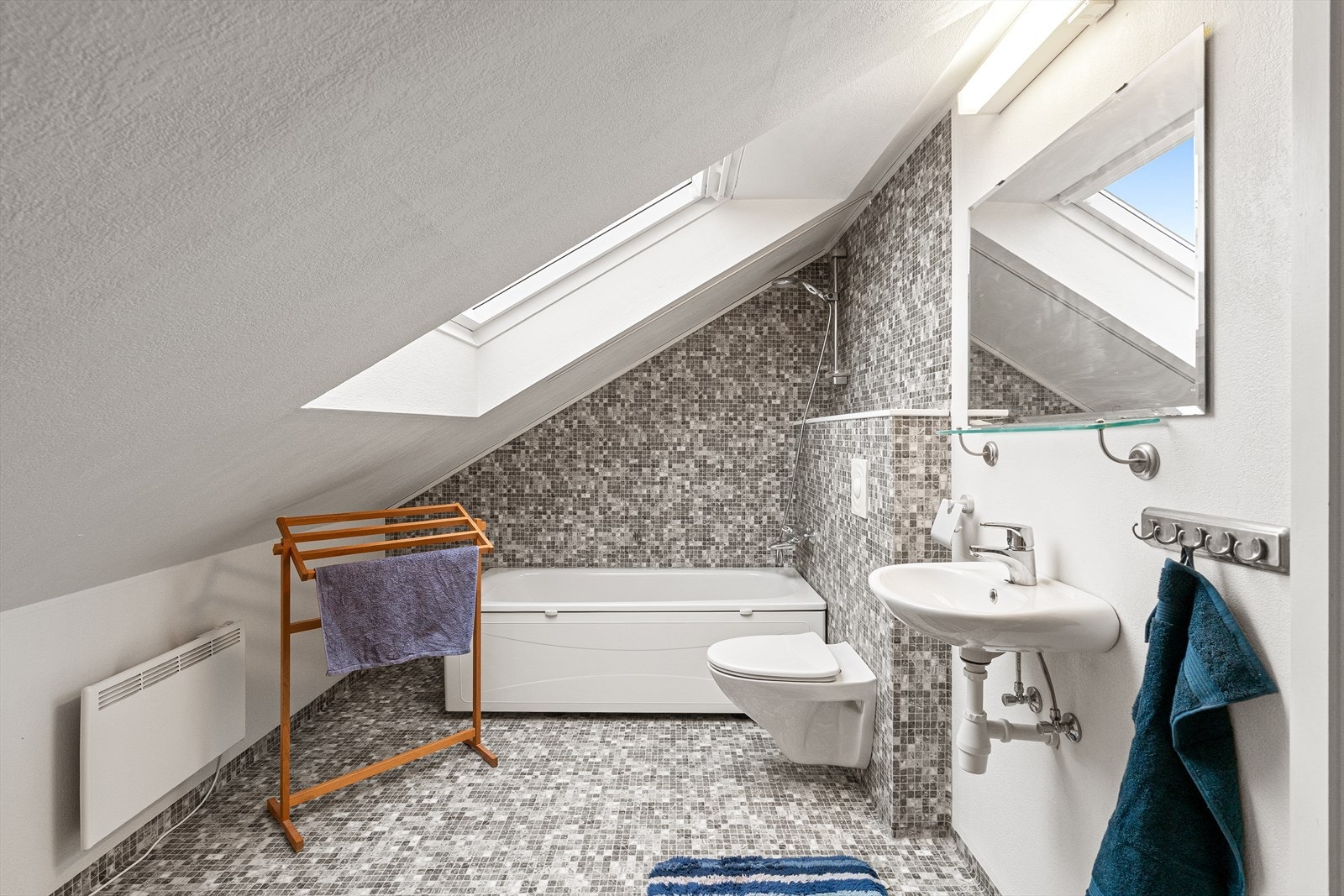 Sjarmerende flislagt bad utstyrt med badekar, vegghengtoalett og servant. Galleribilde