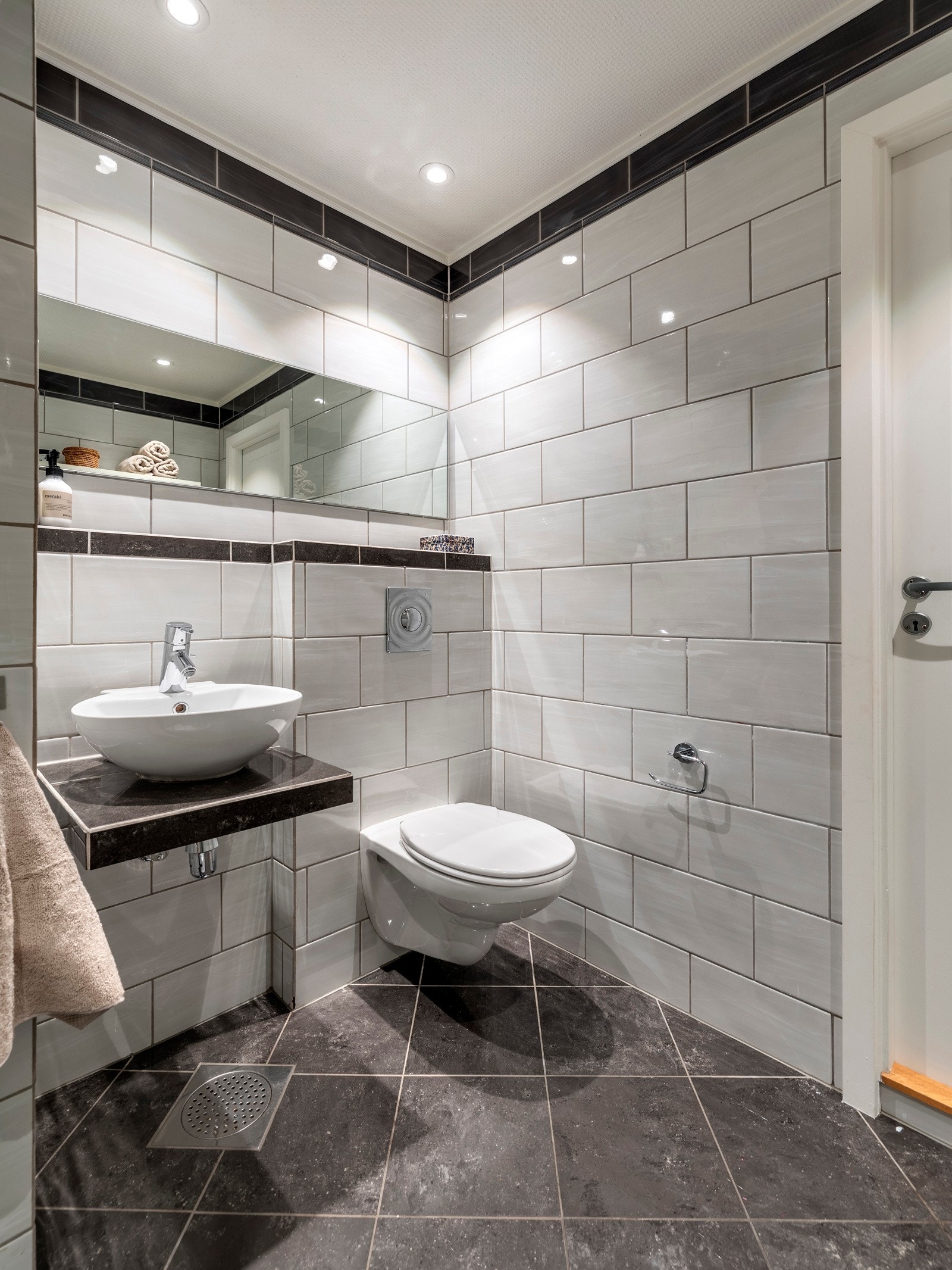 Badet er innredet med plassbygd benk med påsatt bollevask, speil på vegg, vegghengt toalett og et nytt dusjkabinett fra 2025. Galleribilde