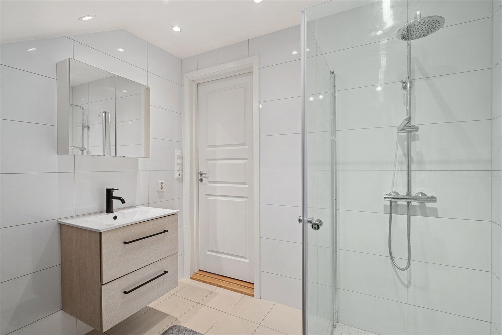 Badet er utstyrt med vegghengt toalett, dusjhjørne med glassvegger, innredning med nedfelt servant, speilskap, samt opplegg for vaskemaskin. Galleribilde