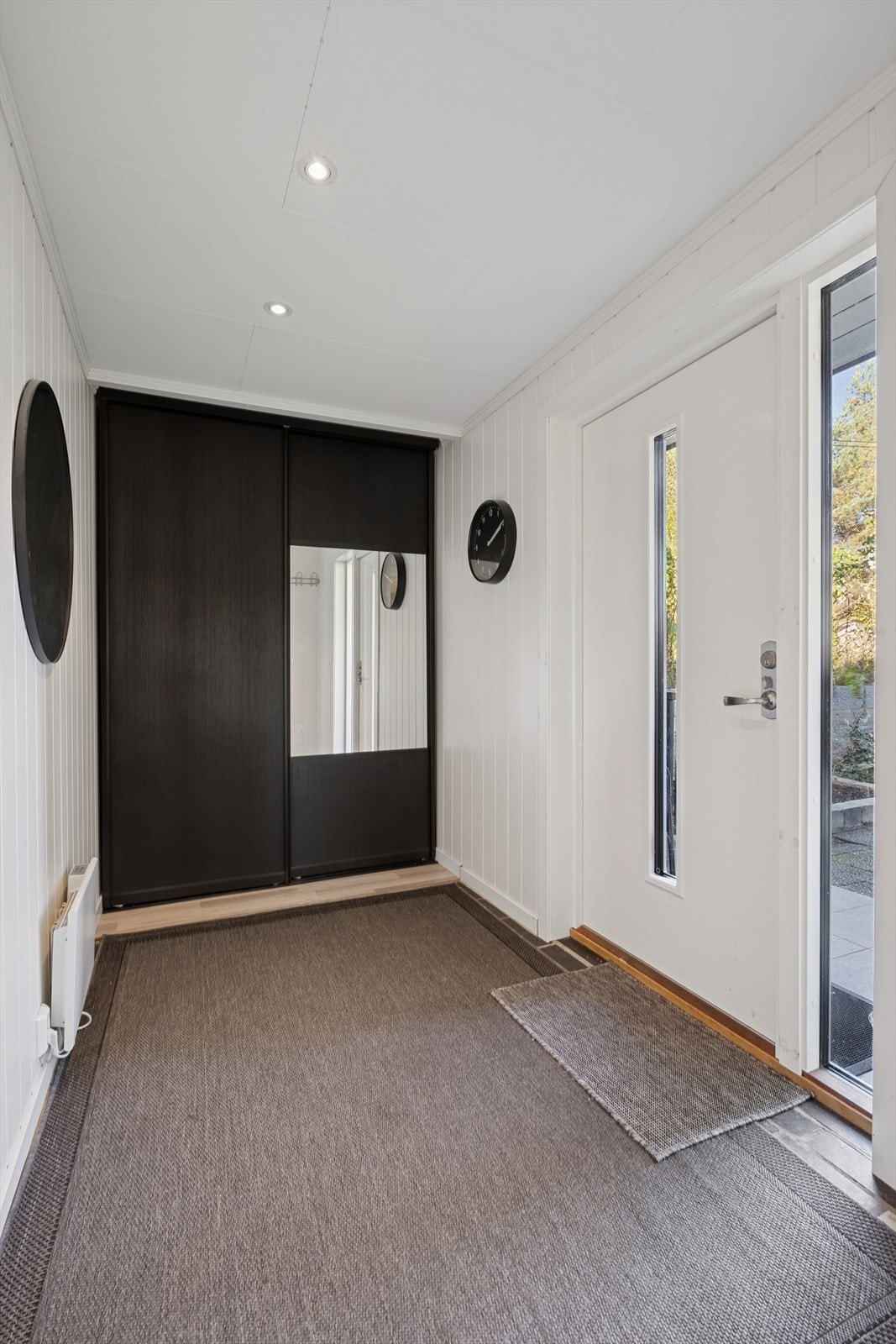 Her ønskes du velkommen inn i entré med plass til å henge fra seg ytterklær i skyvedørsgarderobe. Galleribilde