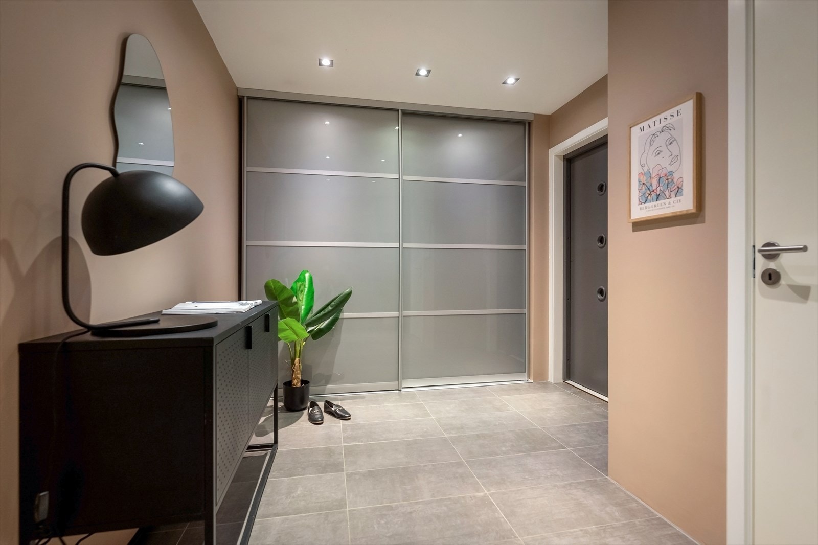 Velkommen inn i en romslig entré med flislagt gulv og en stor skyvedørsgarderobe. Galleribilde