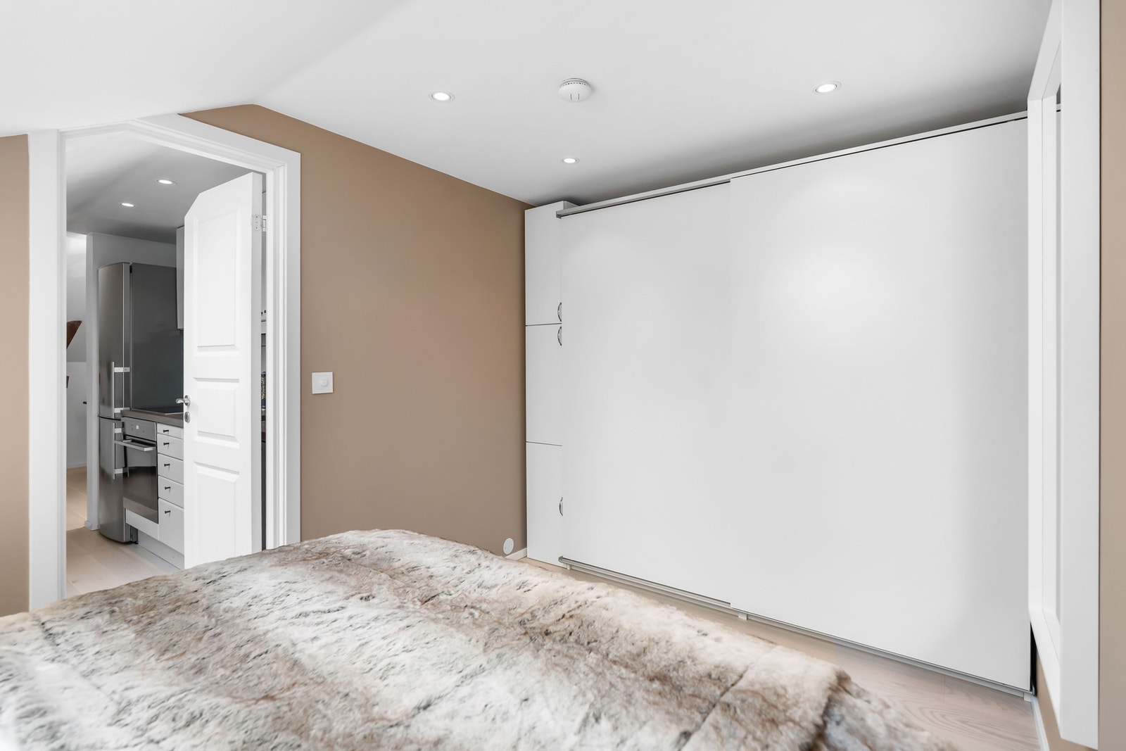 Stor skyvedørsgarderobe og skap langs veggen ivaretar lagringsplassen Galleribilde