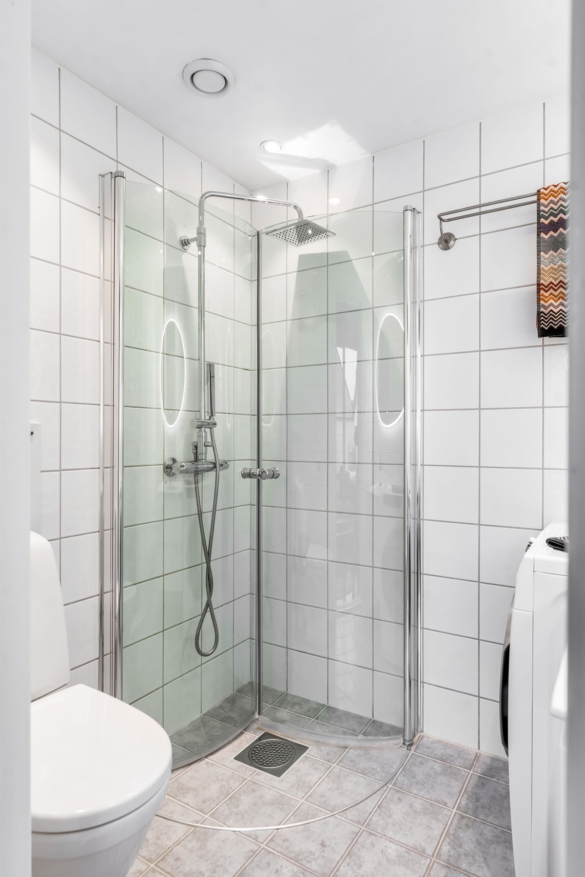 Badet er utstyrt med gulvmontert toalett og dusj med innfellbare dusjvegger i hjørneløsning med regnfallsdusj Galleribilde