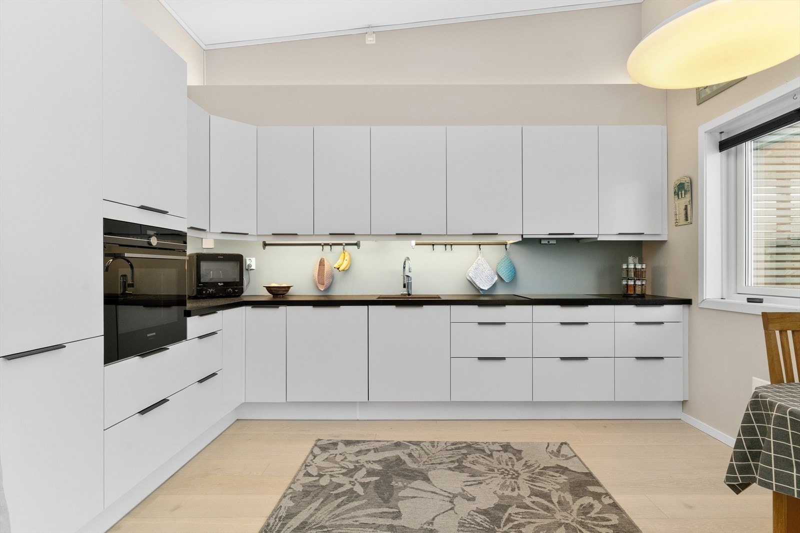 Her er det godt med skaper over og under benken. Benkeplate i kompositt. Integrerte hvitevarer fra Siemens, herunder kjøleskap, oppvaskmaskin, induksjonstopp og stekeovn. Galleribilde