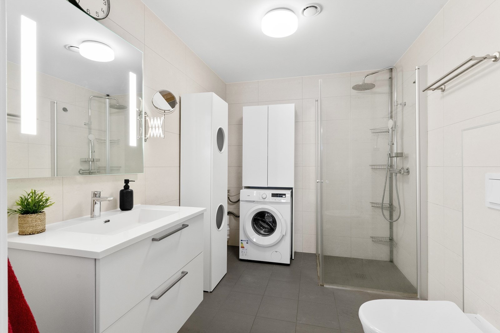 Badet har vegghengt toalett, servant med innredning, dusjhjørne i herdet glass og opplegg for vaskemaskin. Galleribilde