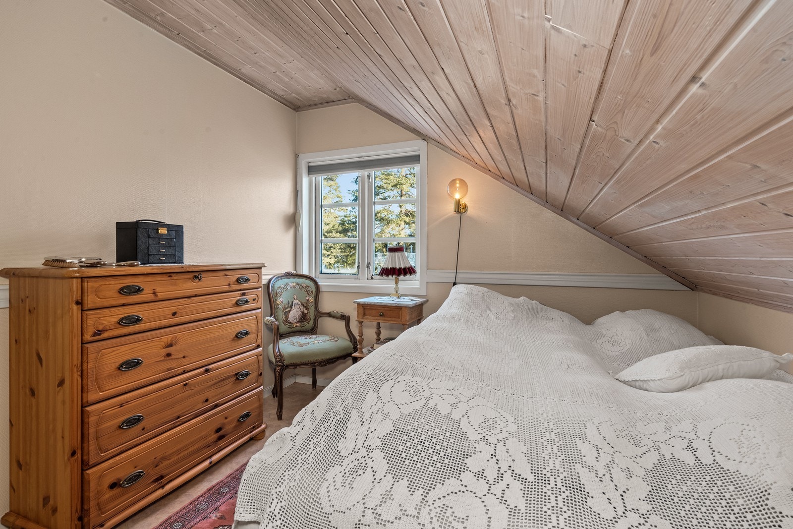 Skråtak med panel gir en lun følelse i soverommet. Galleribilde