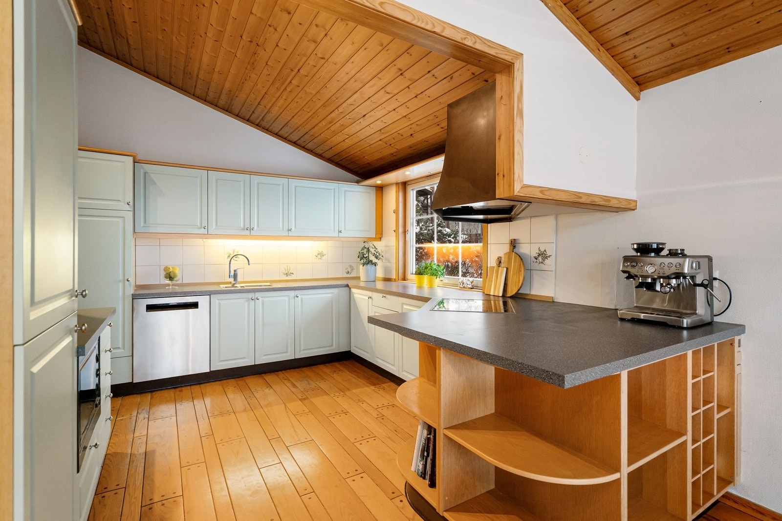 Kjøkkenet er tilliggende stuen og ble fornyet i 2021. Innredningen har profilerte, hvitmalte fronter, benkeplater i laminat og fliser over benk. Galleribilde