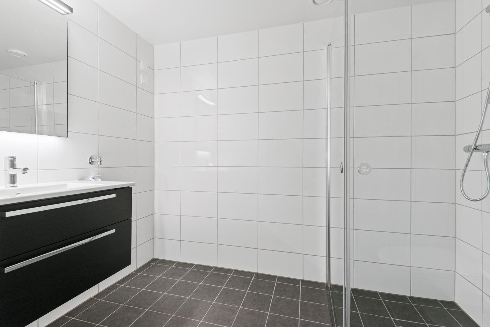 Baderomet er utstyrt med dusj m/ innfelte dører og vegghengt WC. Galleribilde