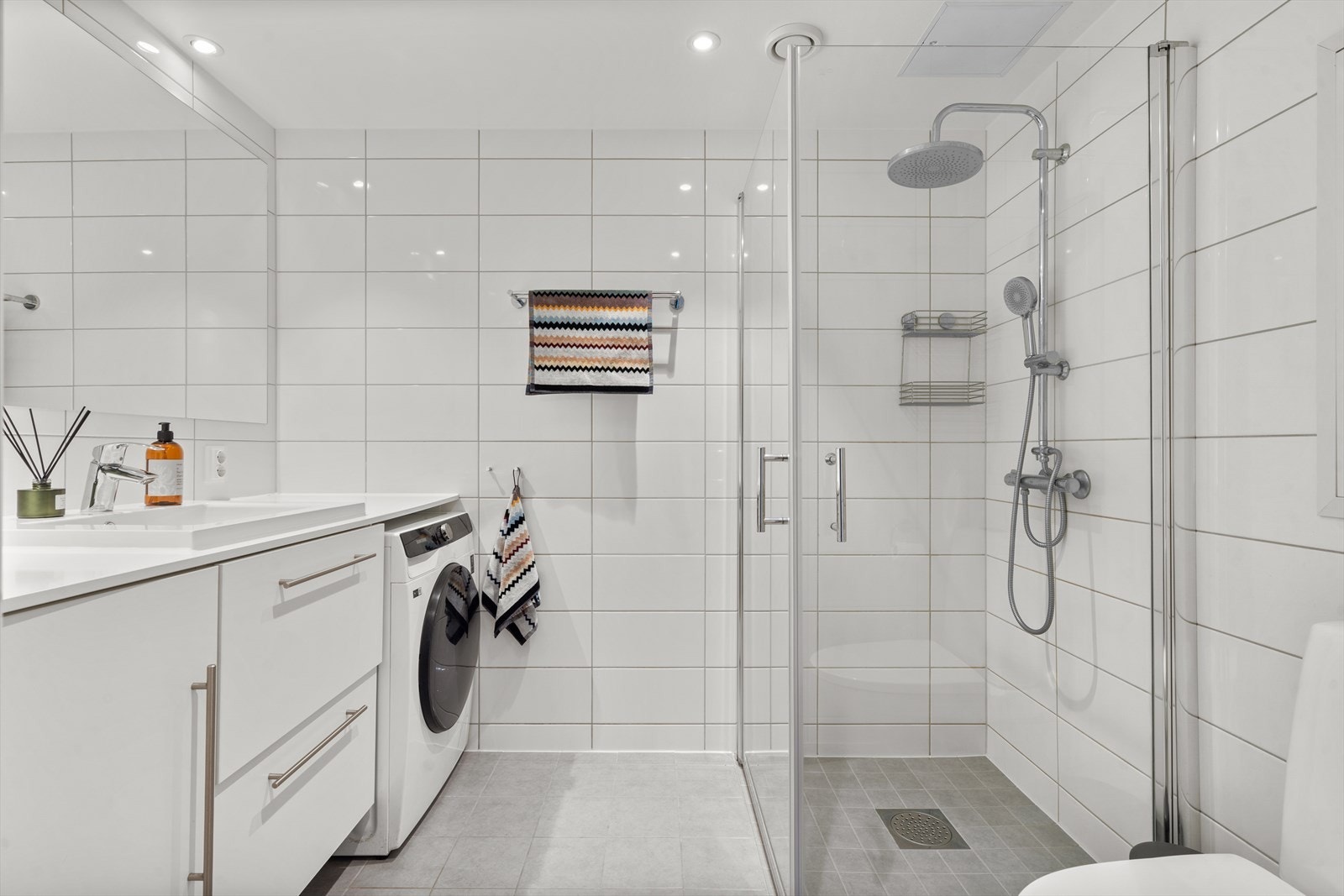 Badet er utstyrt med vegghengt toalett, servantinnredning , ettgreps blandebatteri, dusj med dører i glass, plass og opplegg for vaskemaskin, samt downlights og gulvvarme. Galleribilde