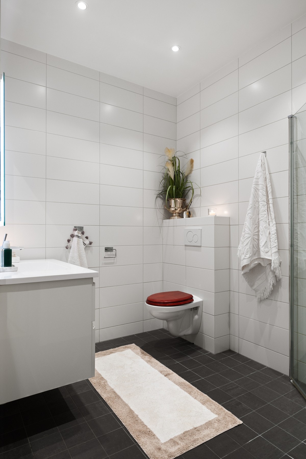 Badet har dusj med glassdører, baderomsinnredning, speil med LED-lys og vegghengt wc. Galleribilde