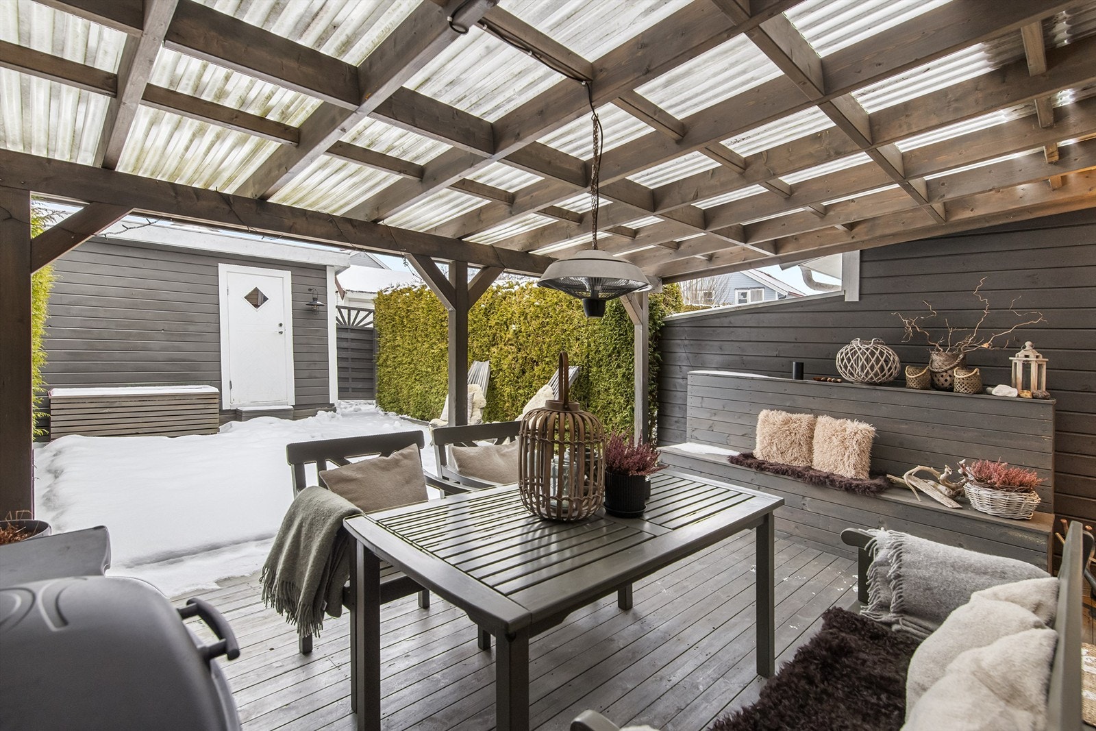 Tomten er opparbeidet med terrassedekke helt til boden og tett hekk mot naboer Galleribilde